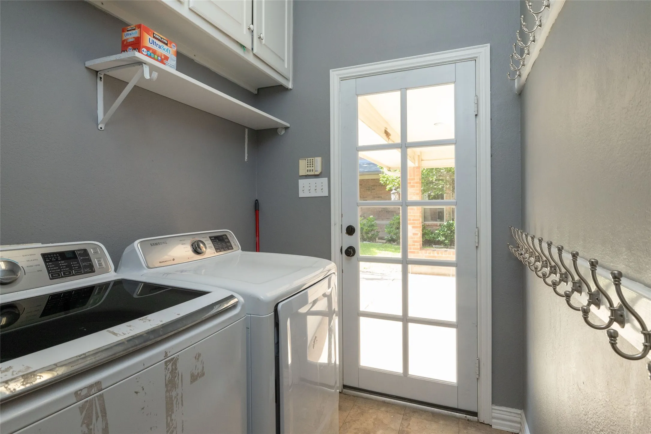 Laundry area featuring a full-light paneled door, built-in shelving, white cabinetry, and a wall-mounted coat rack
