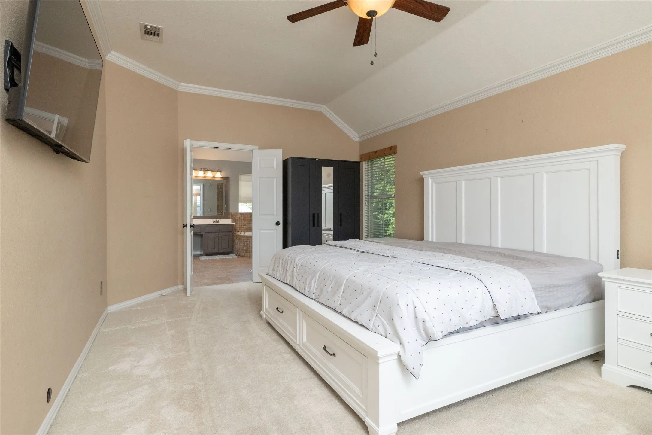 Carpeted bedroom featuring a vaulted ceiling and neutral wall tones