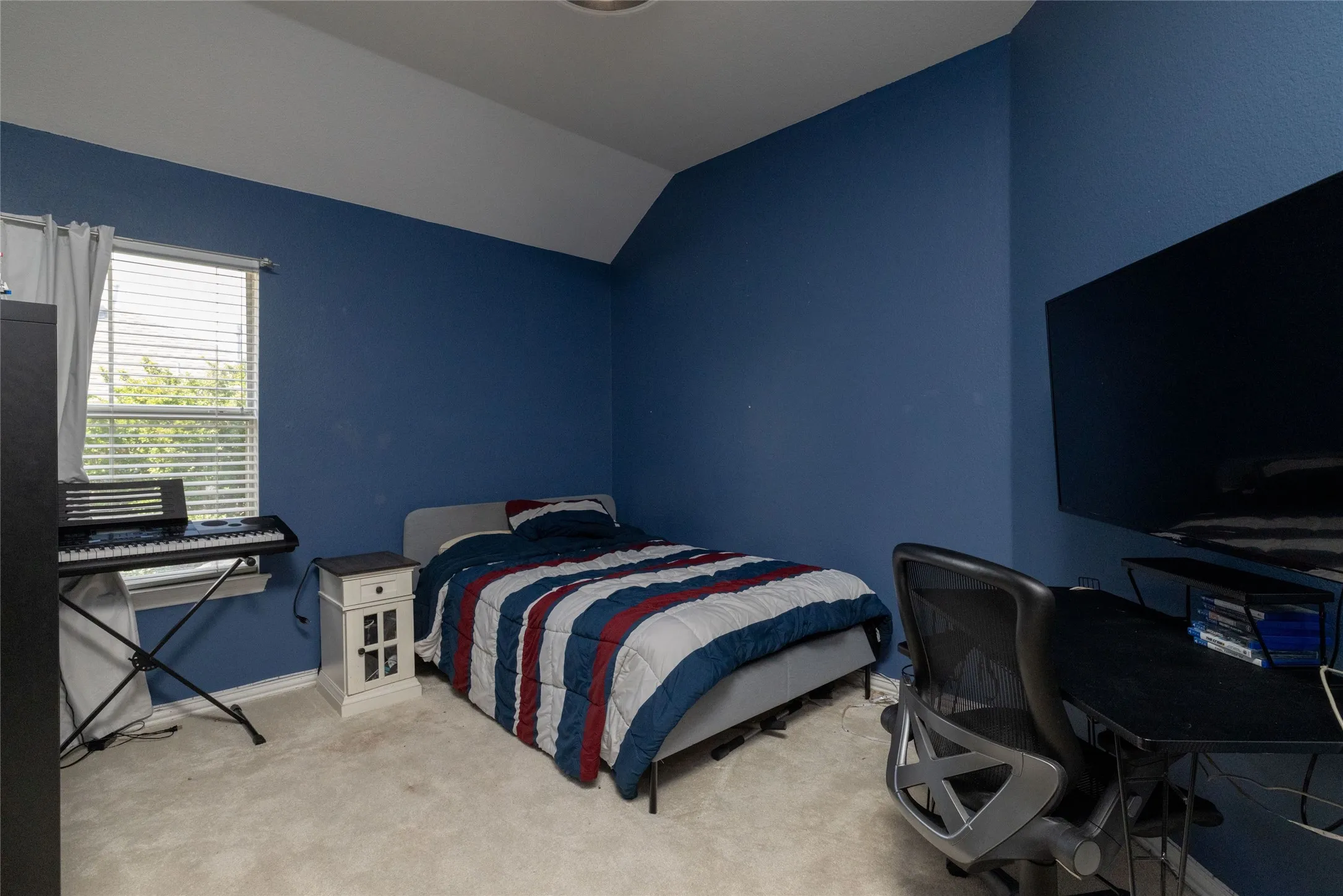 Room featuring textured blue walls and a vaulted ceiling