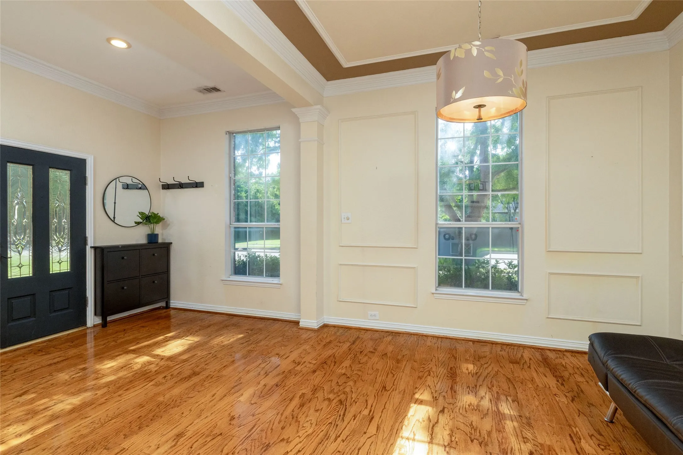 Entryway featuring wood-finish flooring, a dark-paneled front door with decorative glass inserts, and two large windows
