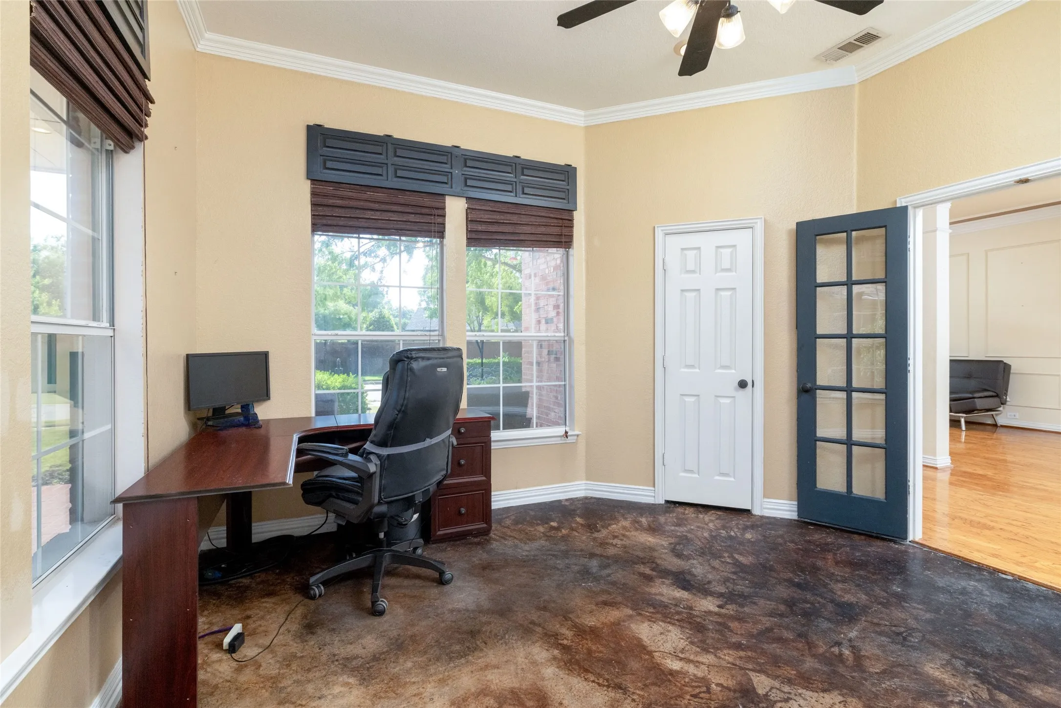 Spacious room featuring broad windows with blinds, a ceiling fan with integrated lighting, a white panel door, and a French door with multiple glass panes