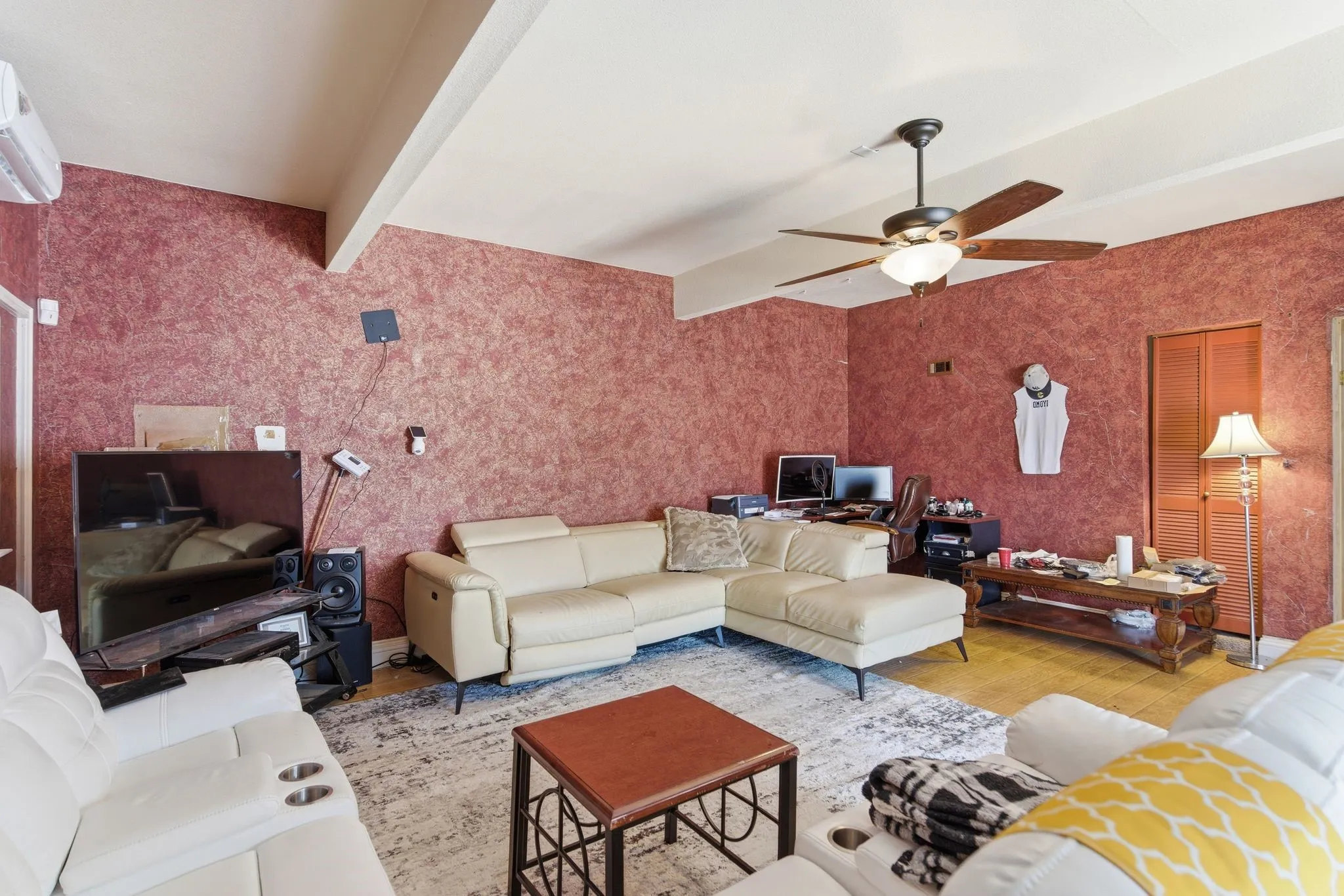 Living area featuring textured wall finish and a ceiling fan with integrated lighting