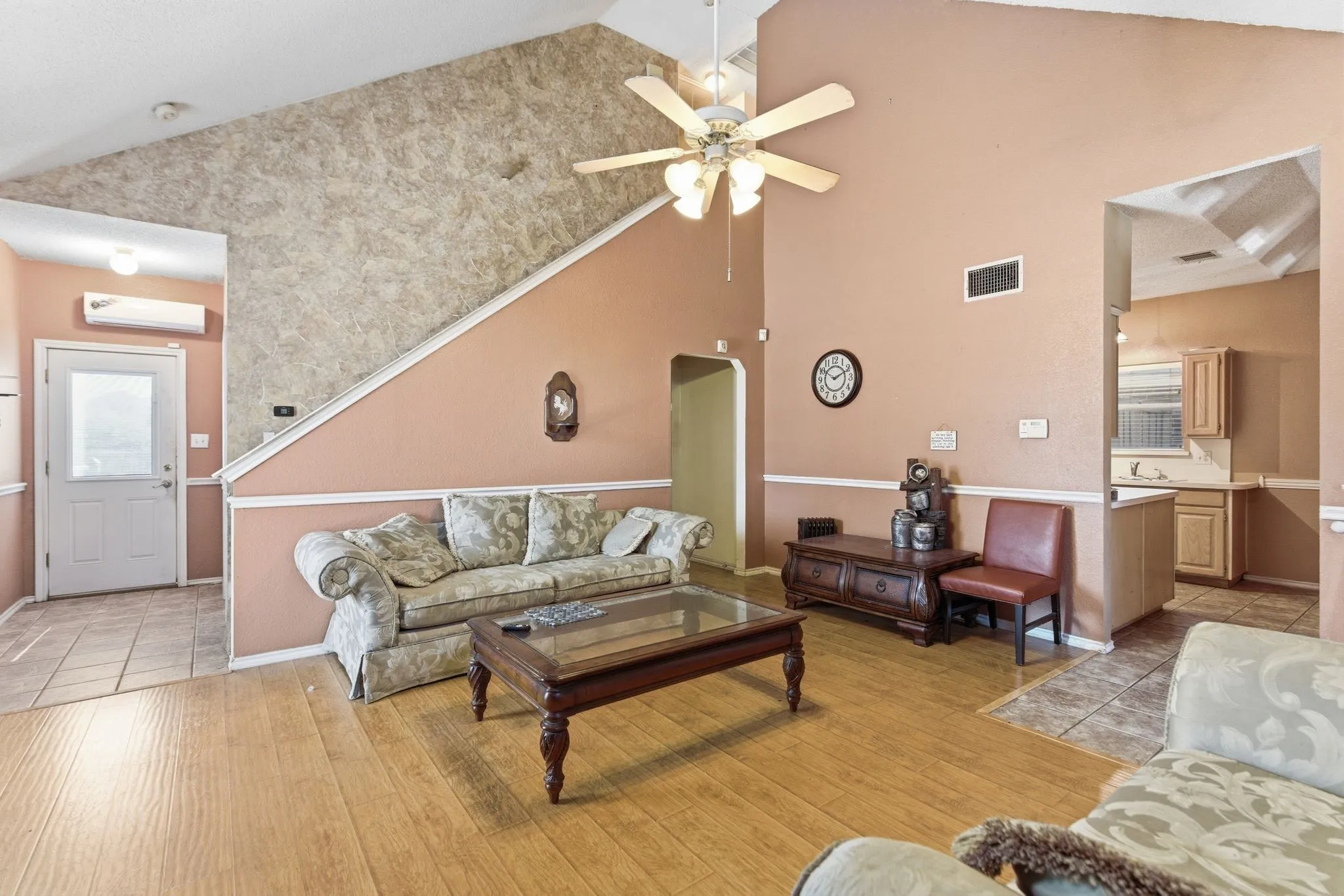 Vaulted ceiling with a ceiling fan, wood-finish flooring, and wainscoting