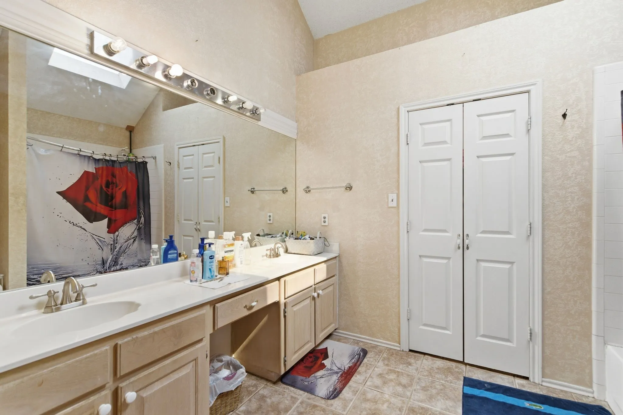 Bathroom featuring a dual vanity with integrated sinks and brushed nickel faucets, extensive wall-mounted mirror, and tile flooring