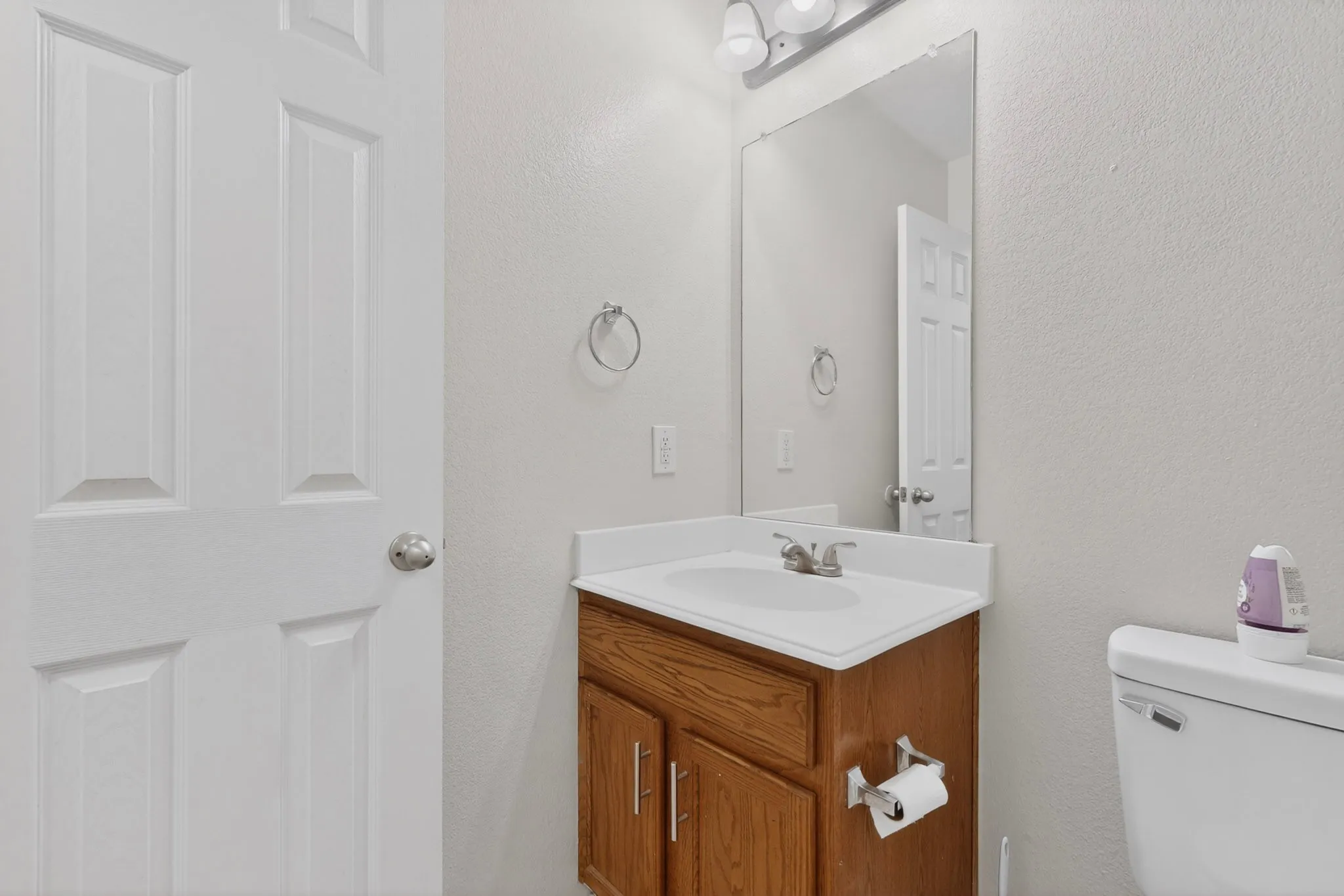Bathroom featuring a wood-finish vanity with an integrated sink and white countertop