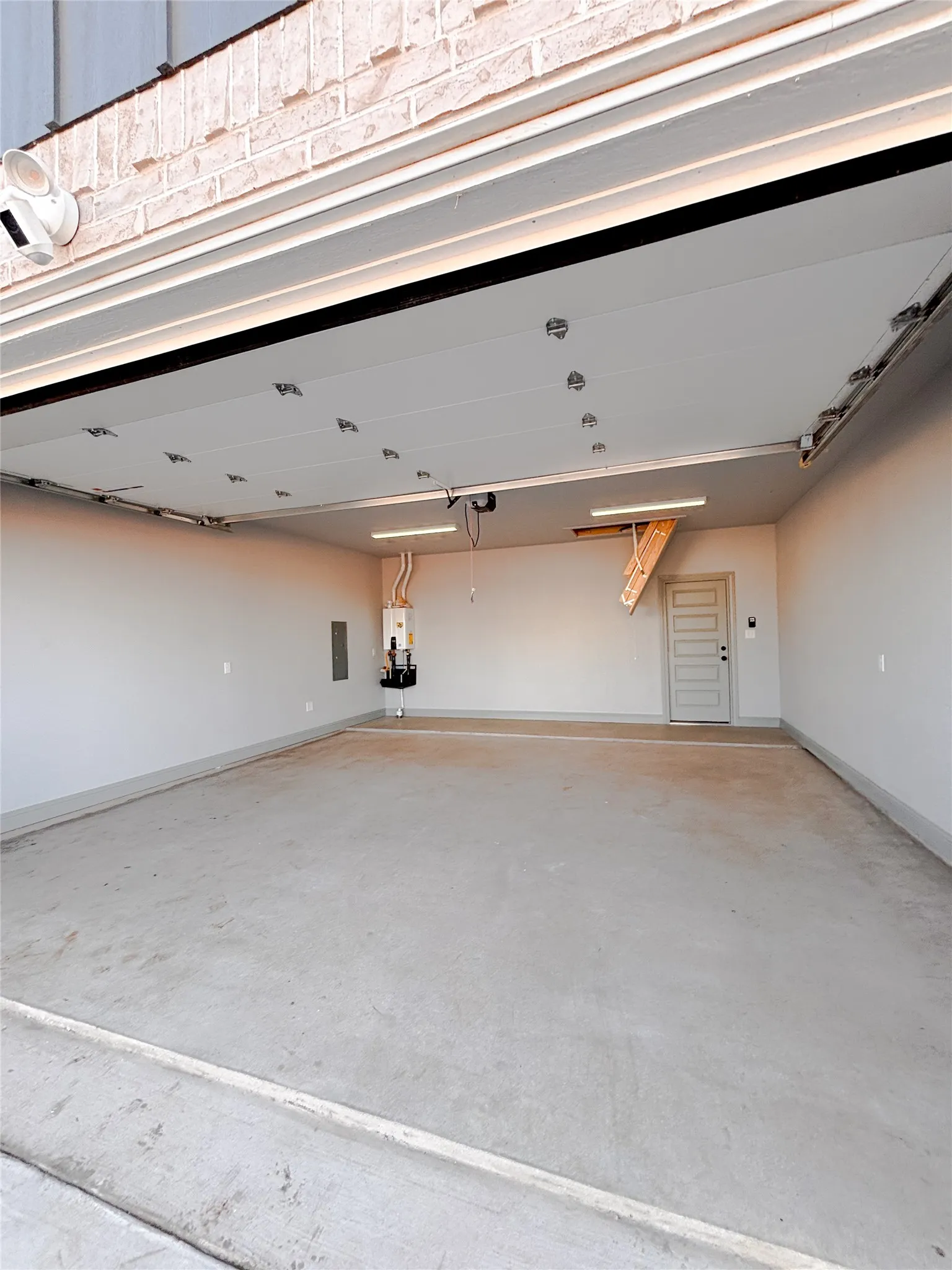 Spacious garage featuring a concrete floor, painted walls, overhead lighting fixtures, and an interior access door