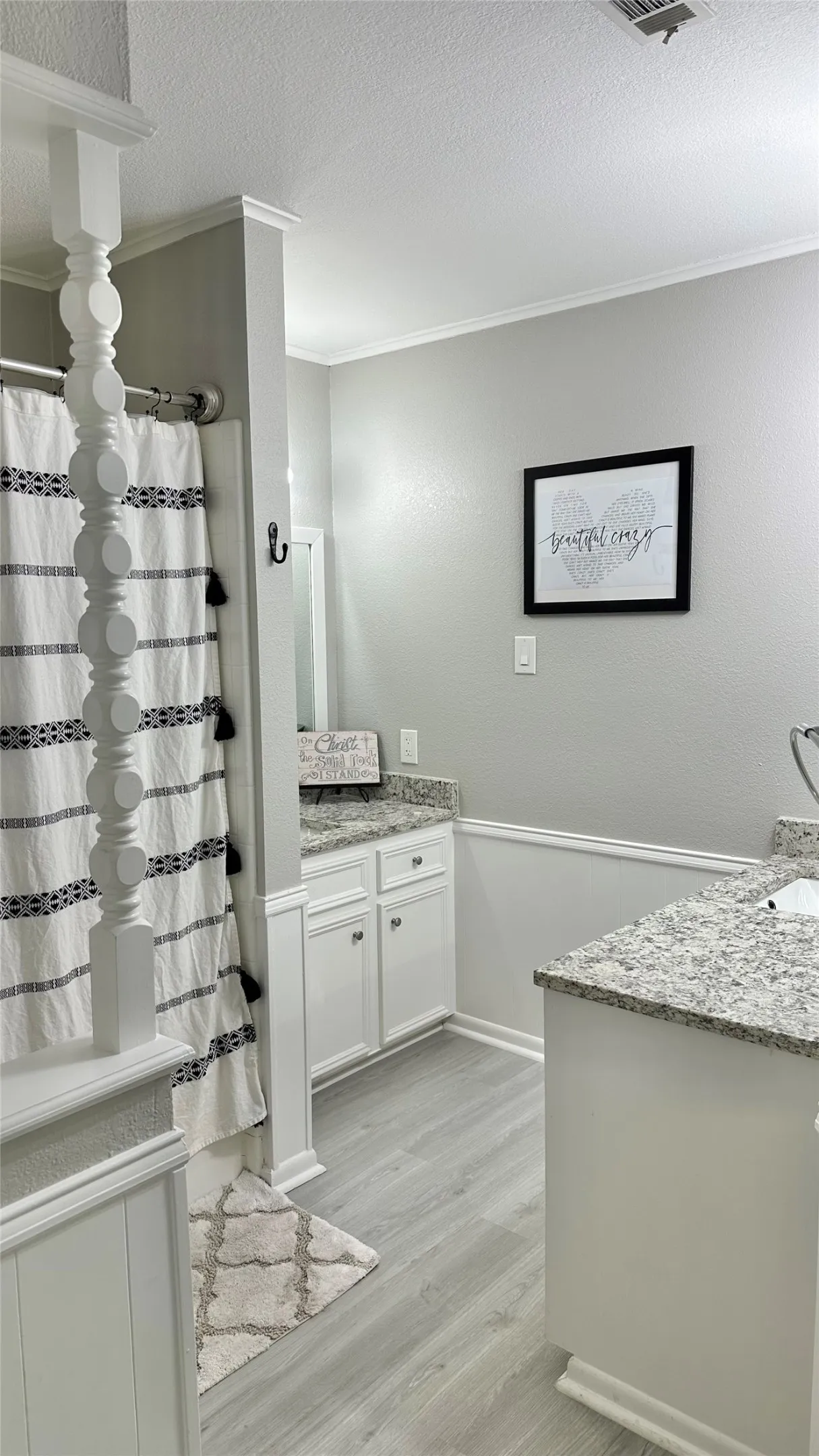 Bathroom featuring light gray wood-finish flooring, white vanity cabinetry with granite countertops, Dual vanities