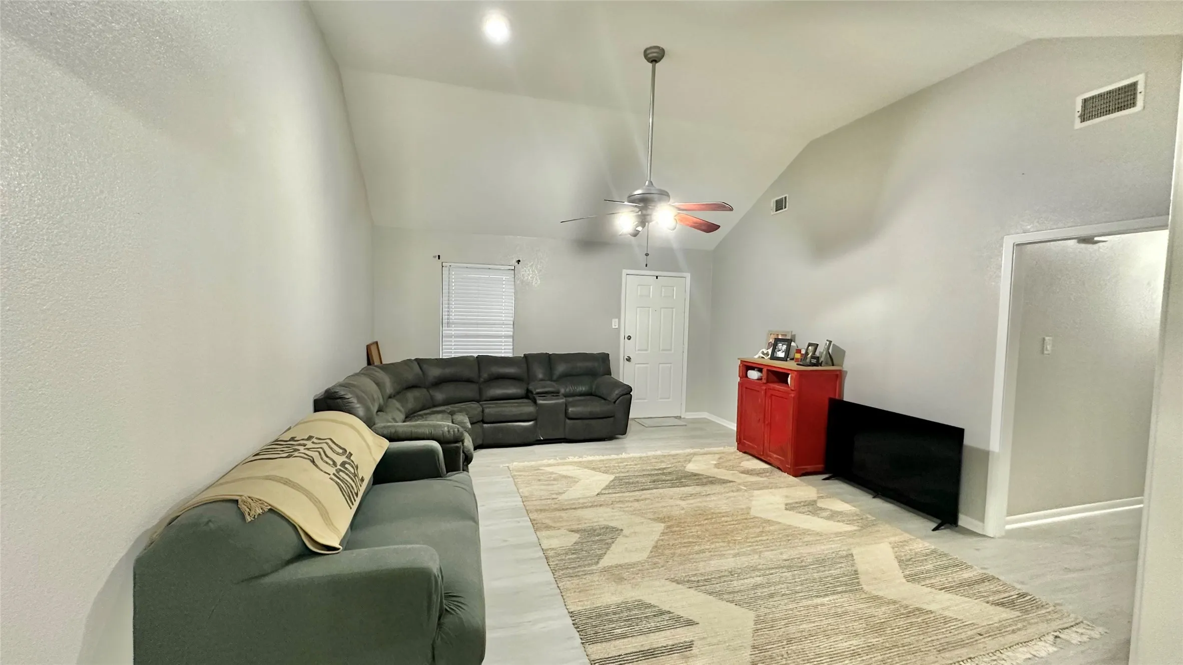 Spacious living area featuring a vaulted ceiling with a ceiling fan, light gray interior
