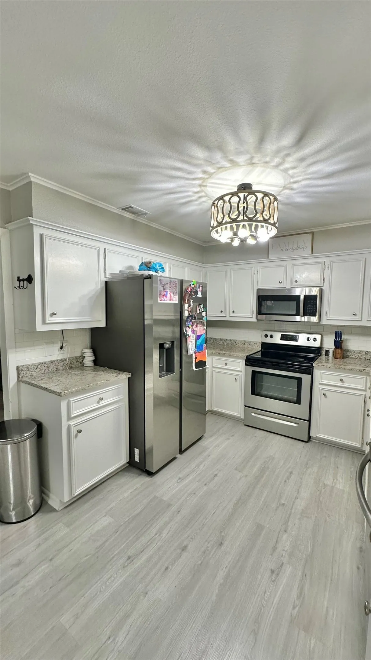 Kitchen featuring white cabinetry, light-toned granite countertops, stainless steel appliances