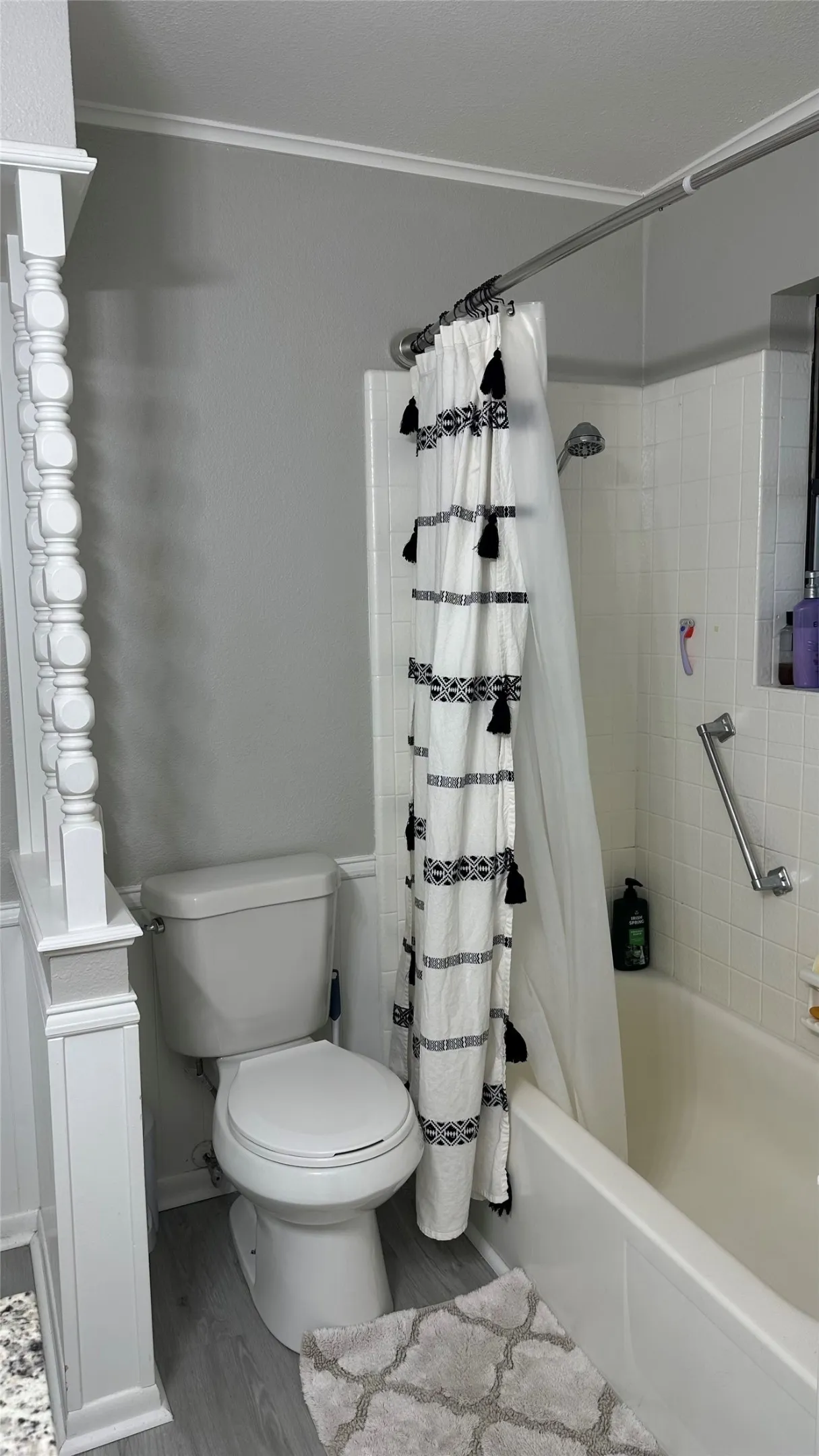 Bathroom featuring a white toilet, full bathtub with shower, white subway tile molded surround
