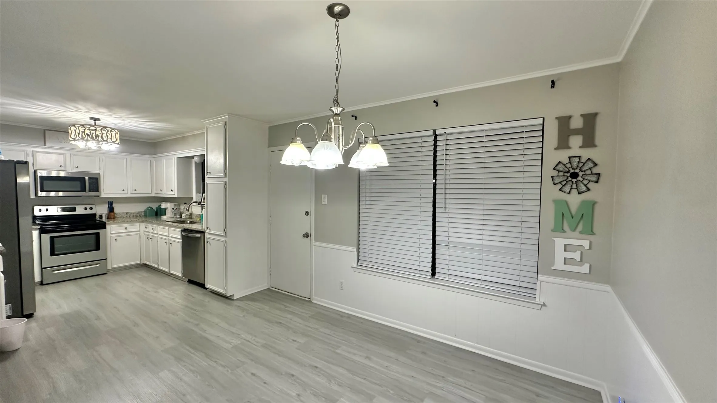 Open-concept kitchen and dining area featuring light-toned wood-finish flooring