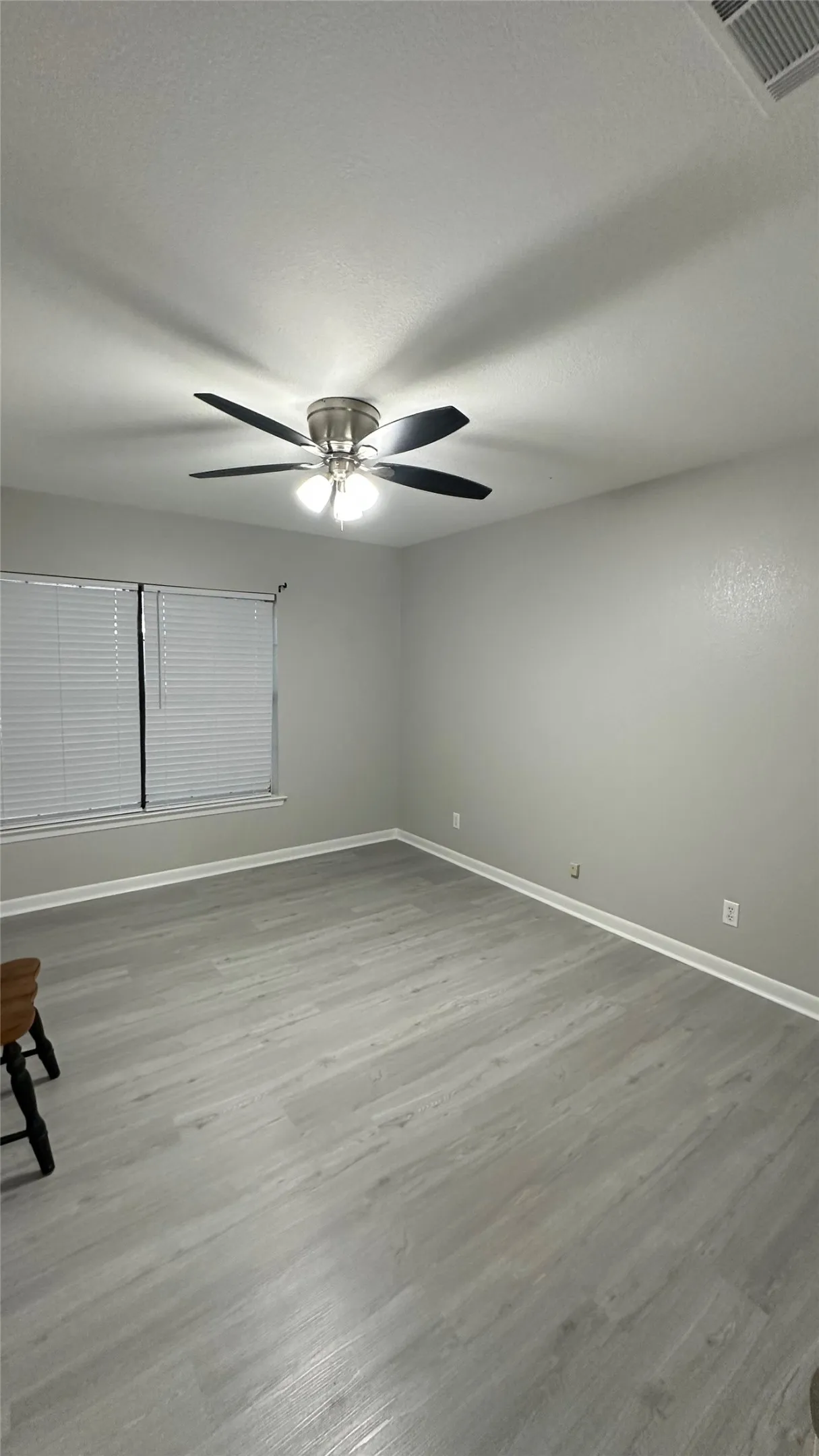 Bedroom 3, neutral gray walls, a window with horizontal blinds, and a ceiling fan with integrated lighting