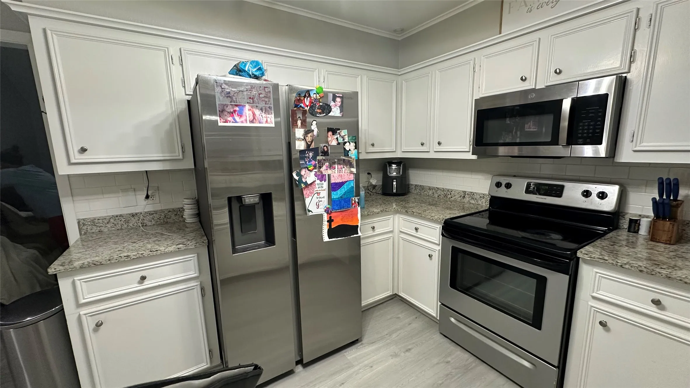 Kitchen featuring white cabinetry with silver hardware, granite countertops, and a subway tile backsplash