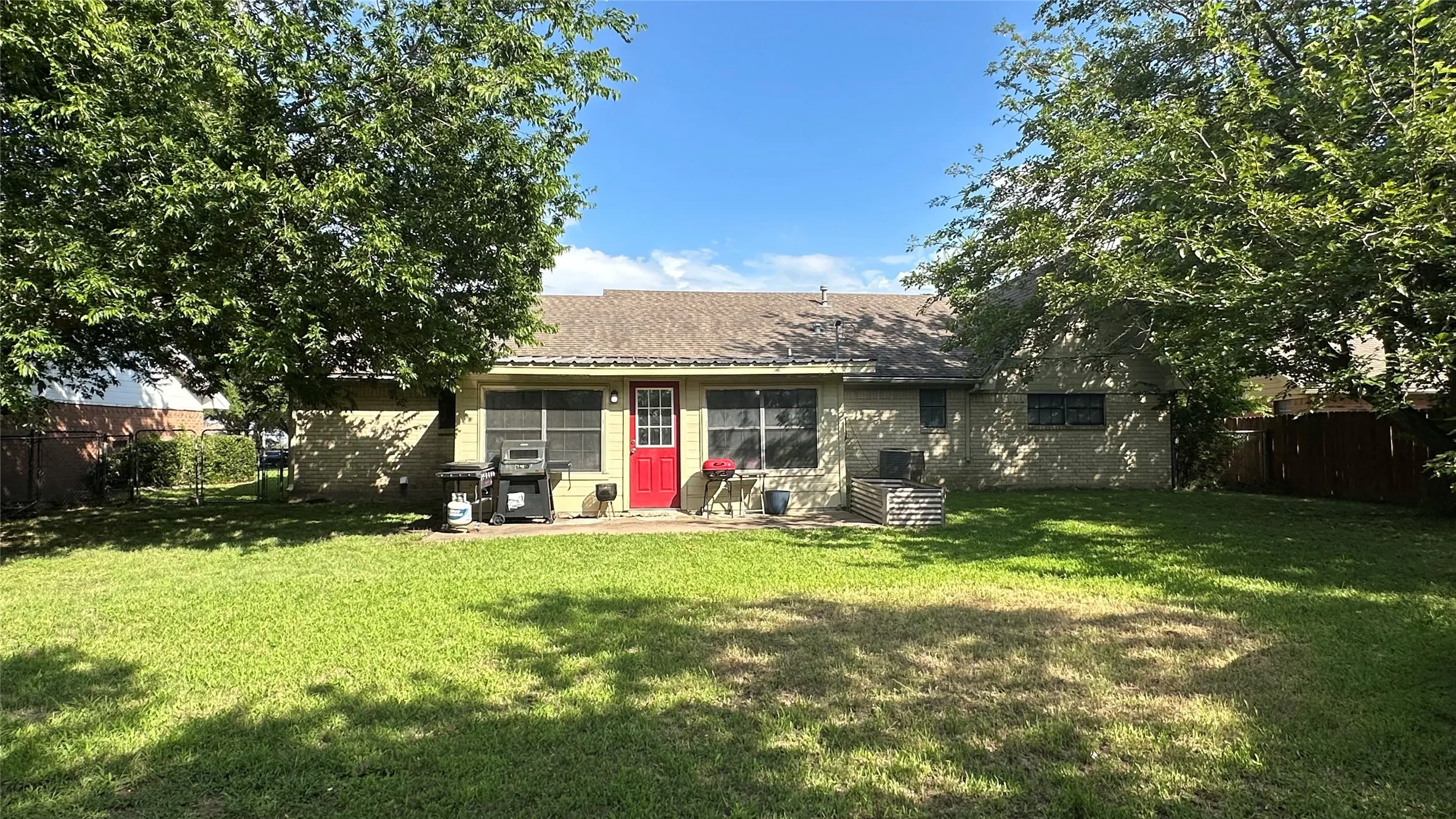 Expansive green lawn with mature trees and a rear patio