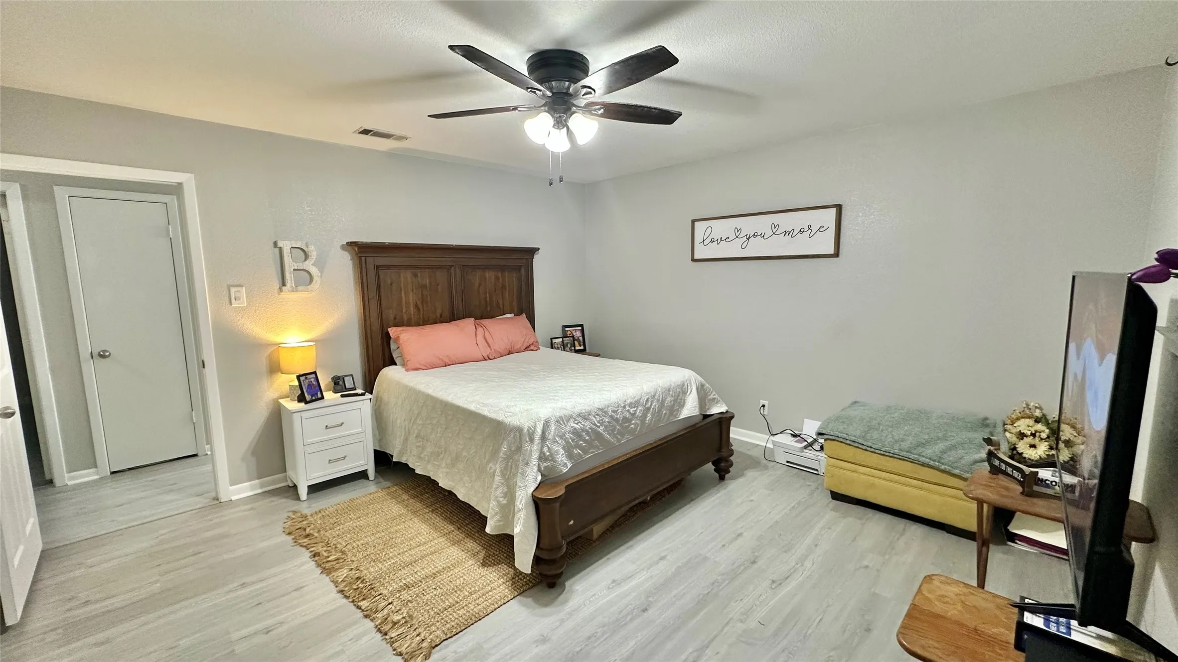 Spacious room featuring light wood-finish flooring and a ceiling fan with integrated lighting
