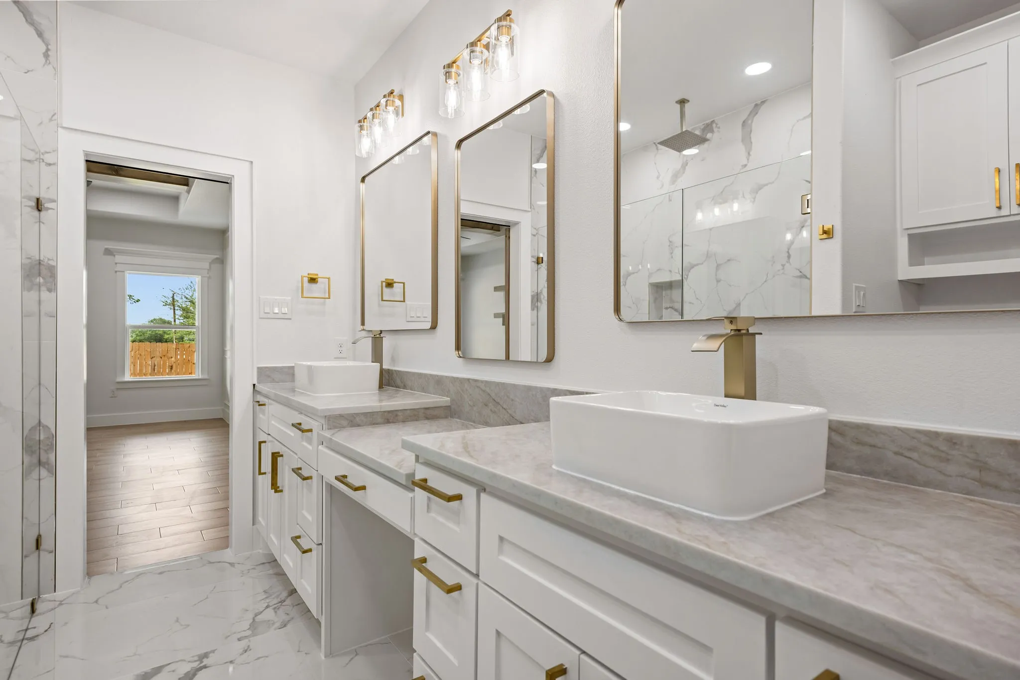 Double vanity with white cabinetry, gold-toned hardware, and rectangular vessel sinks