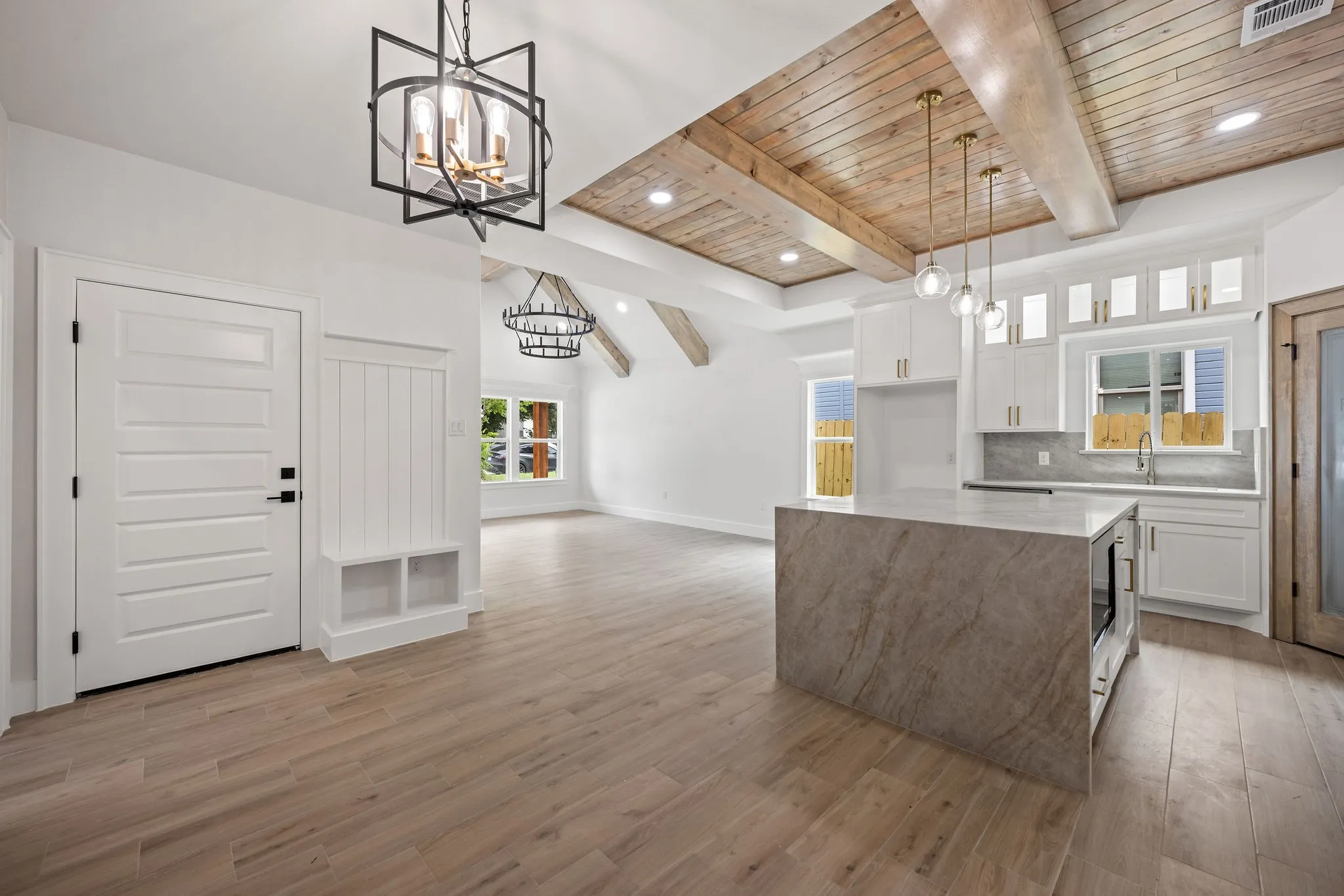Open-concept space featuring a kitchen island with integrated microwave, white cabinetry, and wood-finish flooring