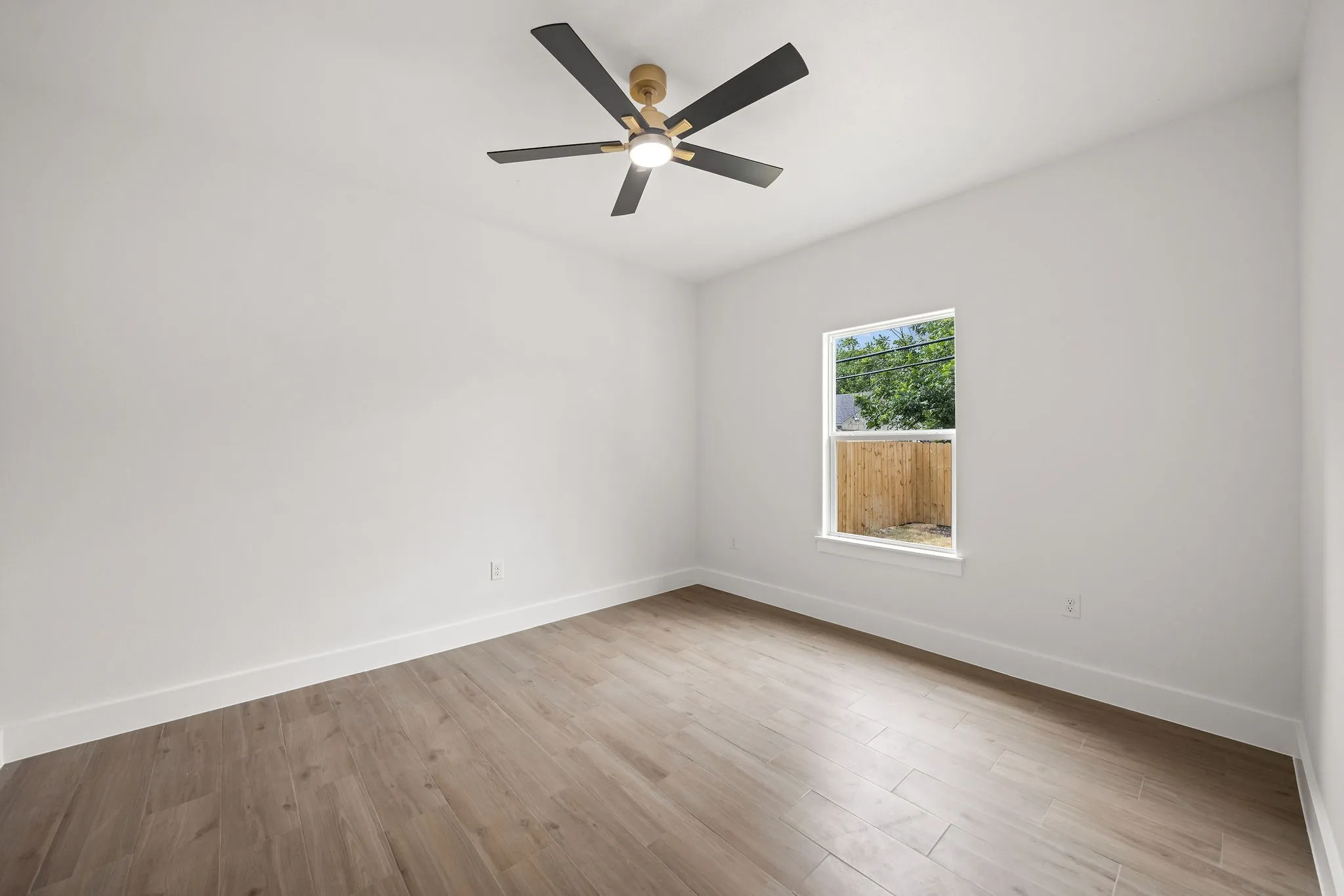 Bright room featuring wood-finish flooring, a contemporary ceiling fan, and crisp white walls
