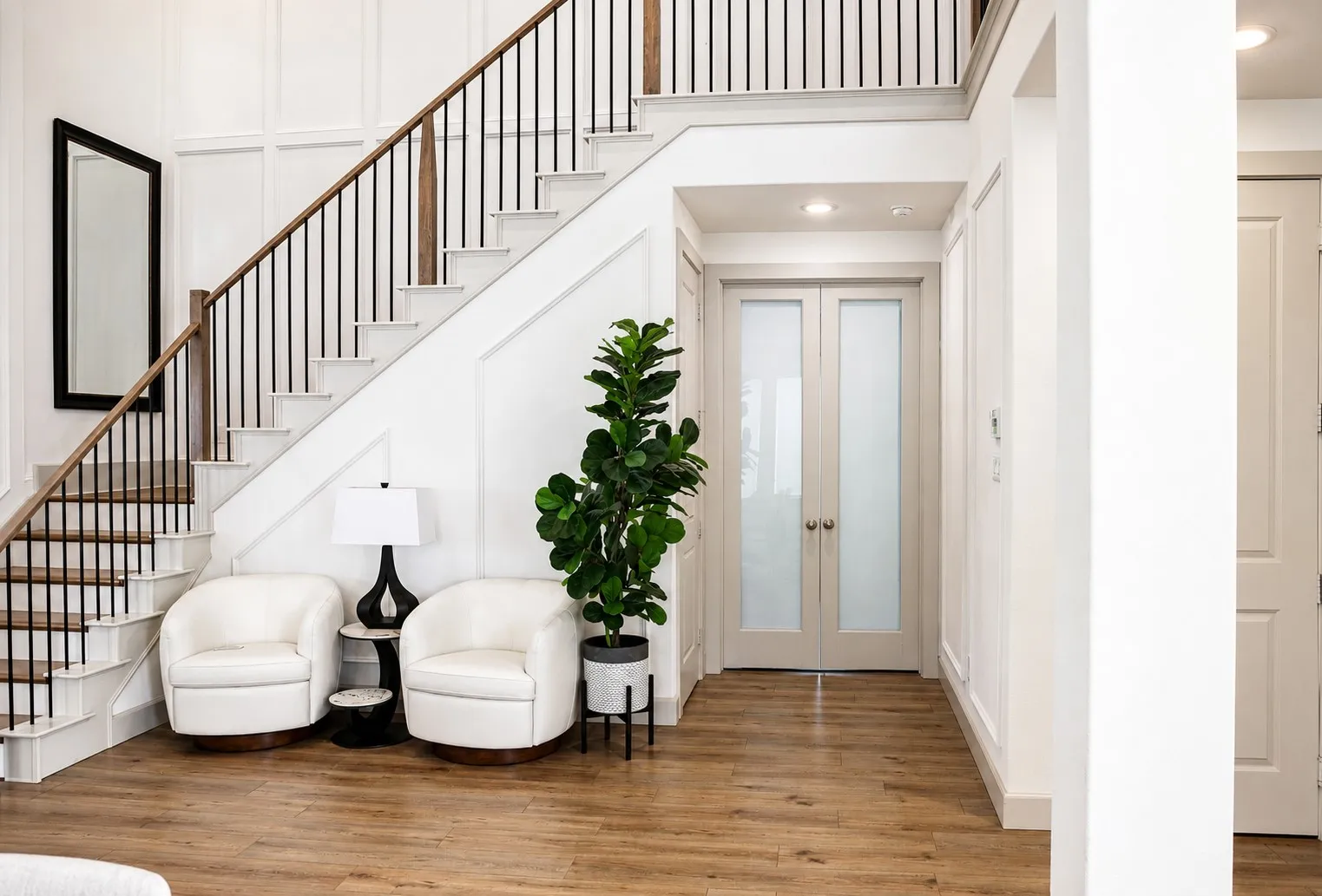 Grand staircase featuring a dark wood handrail, black metal balusters, and white risers