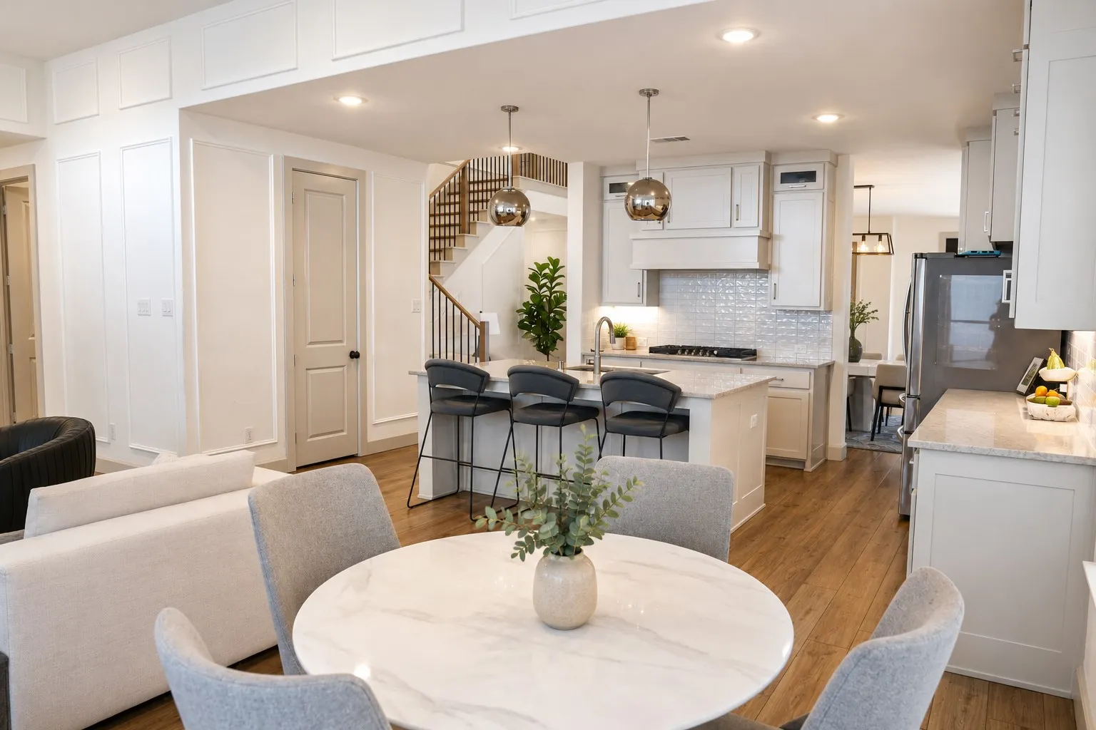 Open-concept kitchen featuring wood-finish flooring, white cabinetry, a kitchen island with seating, a gas range, and a stainless steel refrigerator