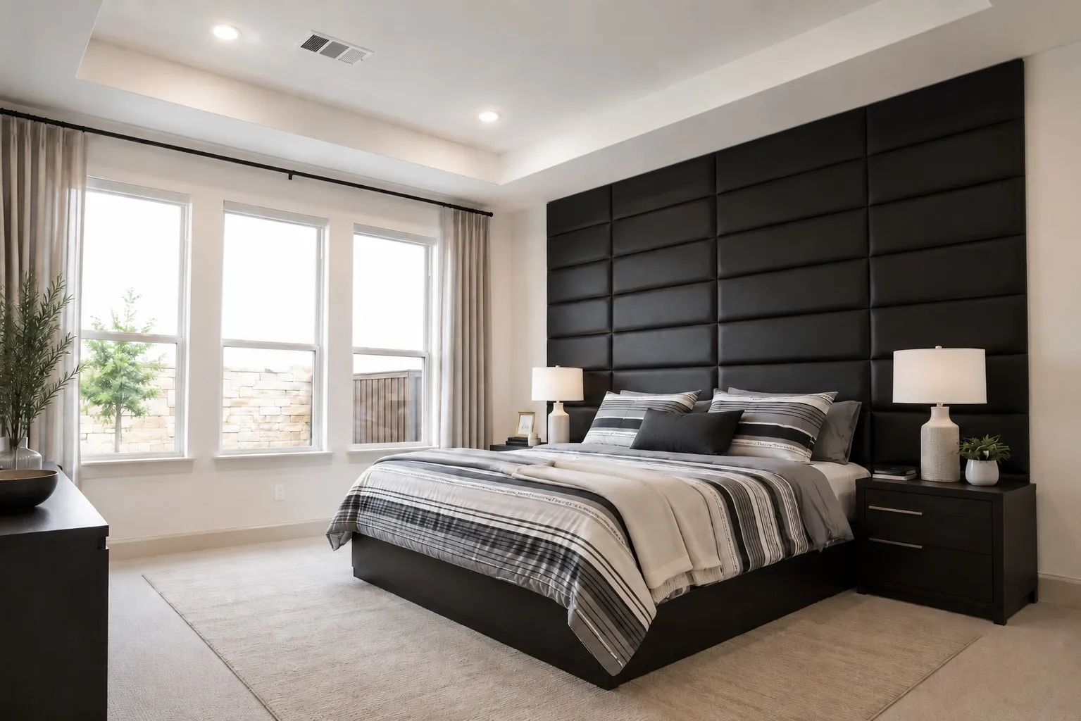 Spacious room featuring a full-height paneled accent wall, a tray ceiling with recessed lighting, three large windows, and light-toned carpeting
