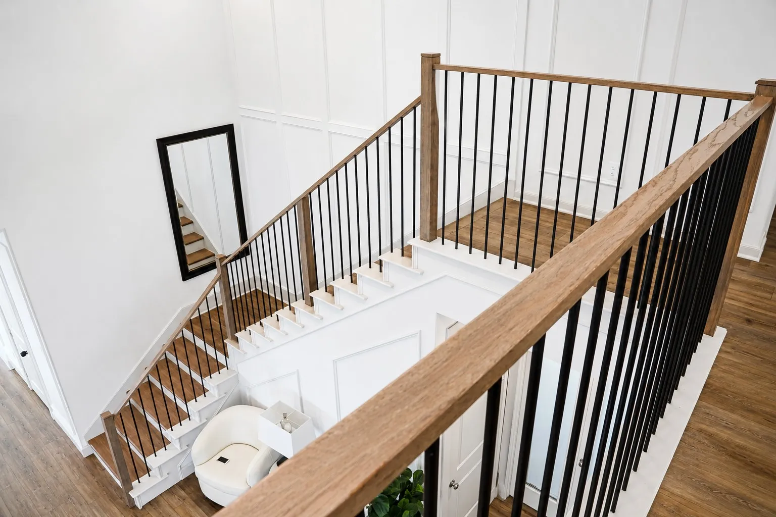 Open staircase featuring wood-finish treads, white risers, and a black wrought iron baluster system with wood-finish handrails