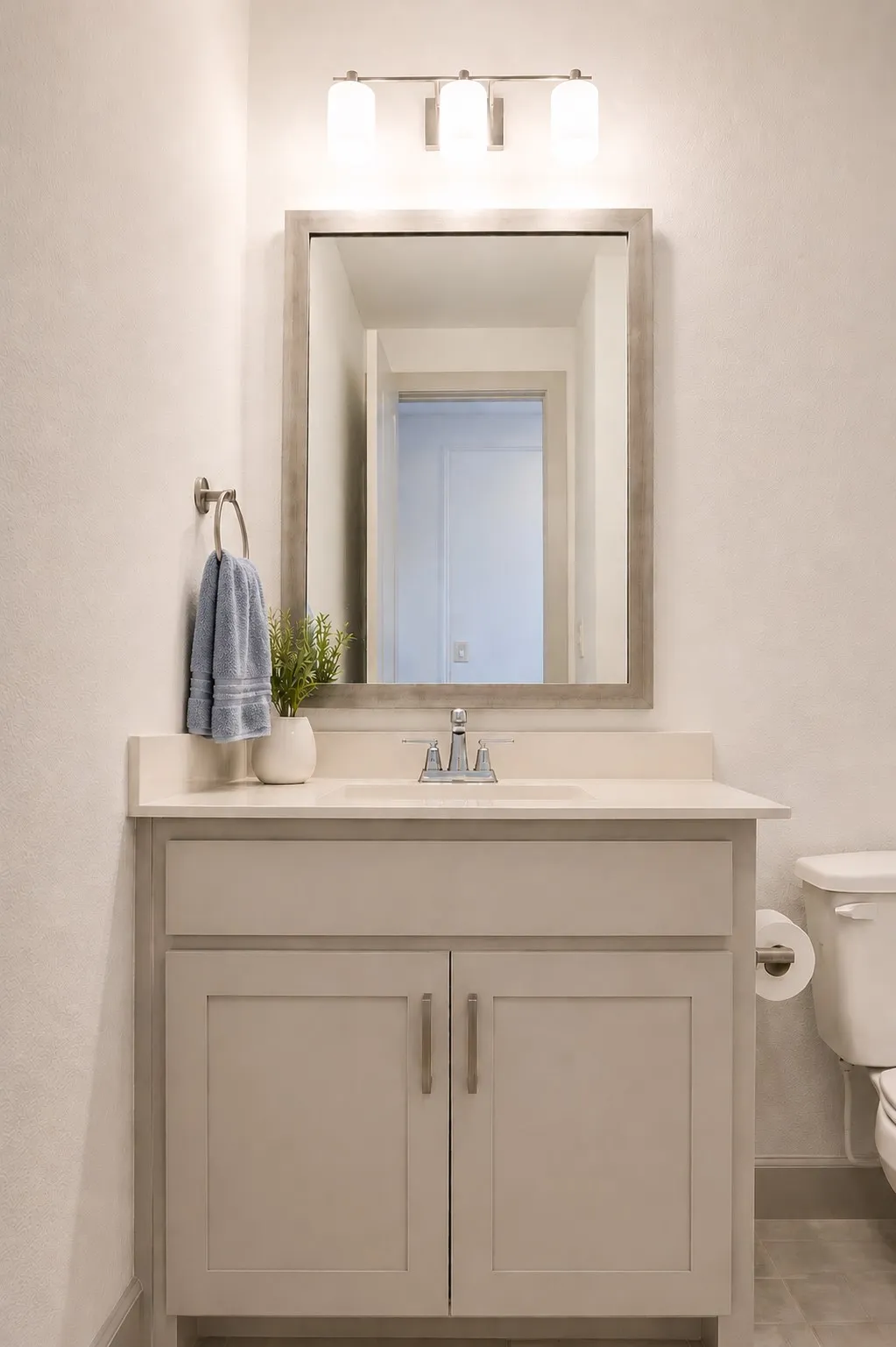 Bathroom vanity featuring a light-toned countertop, integrated sink, and brushed nickel faucet