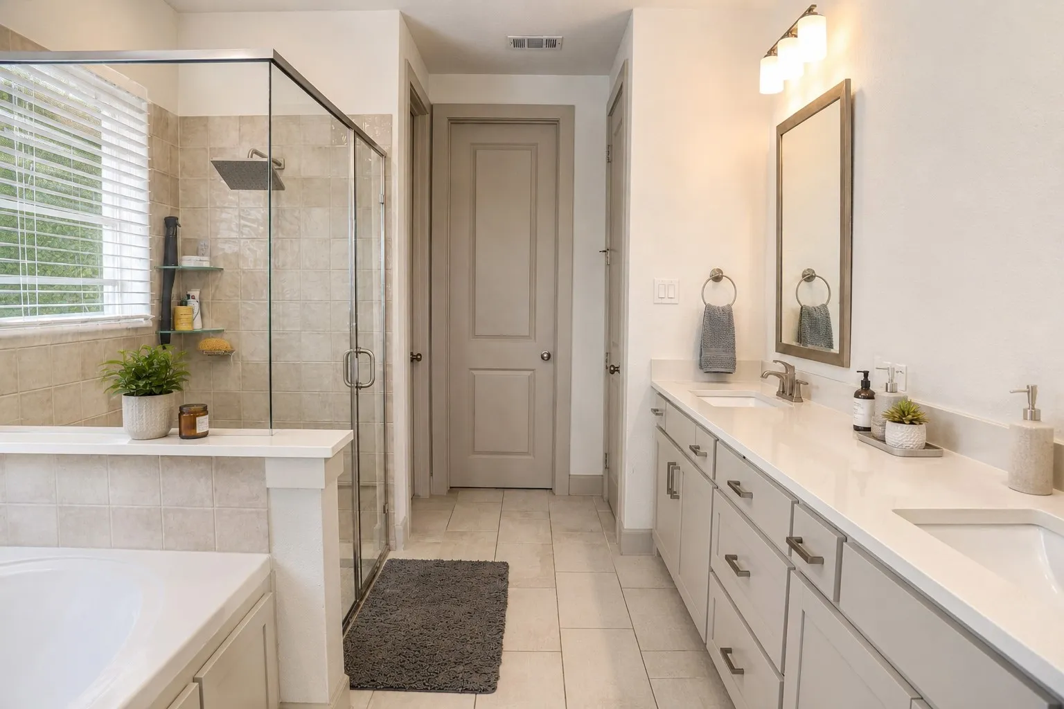 Full bathroom featuring a dual vanity with light-colored countertops, tiled flooring, a glass-enclosed shower with a rain showerhead, and a separate built-in bathtub