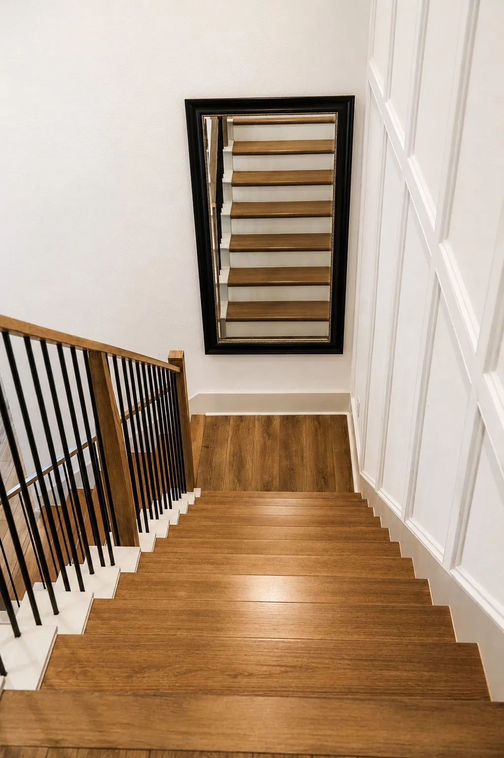 Staircase featuring wood-finish treads and risers, black metal balusters, and a wood-finish handrail
