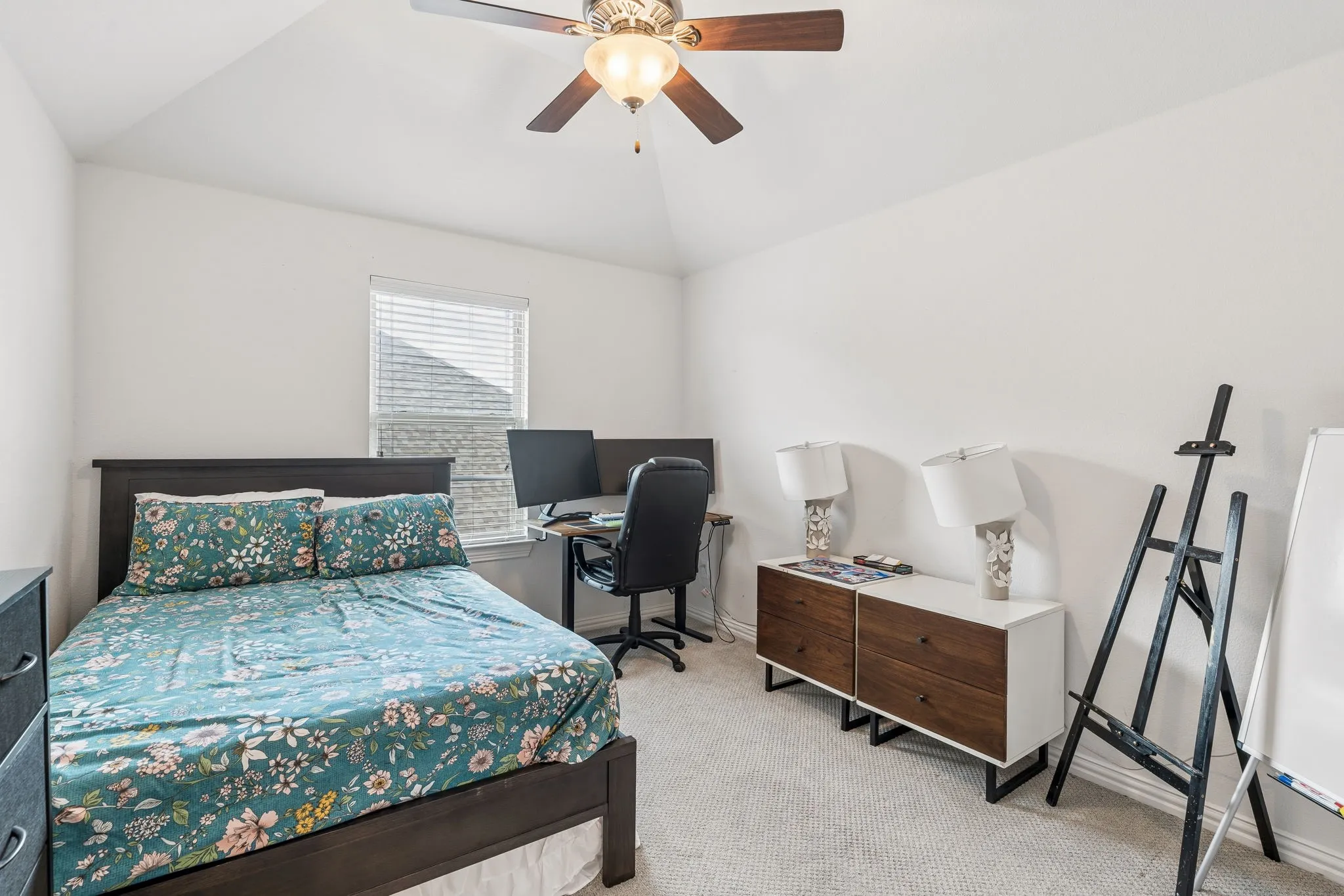 Carpeted interior room featuring a vaulted ceiling and a ceiling fan with integrated lighting