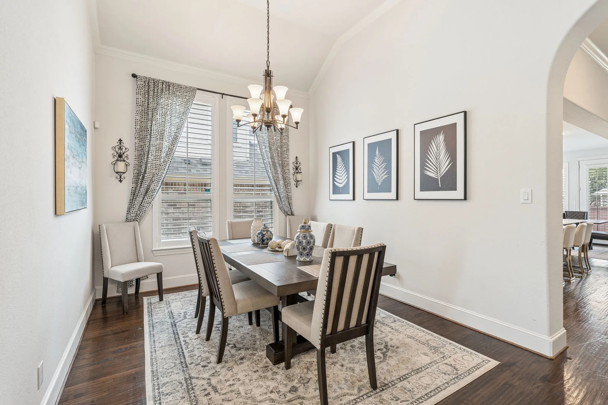 Formal dining space featuring dark wood-finish flooring, a vaulted ceiling, and an arched doorway