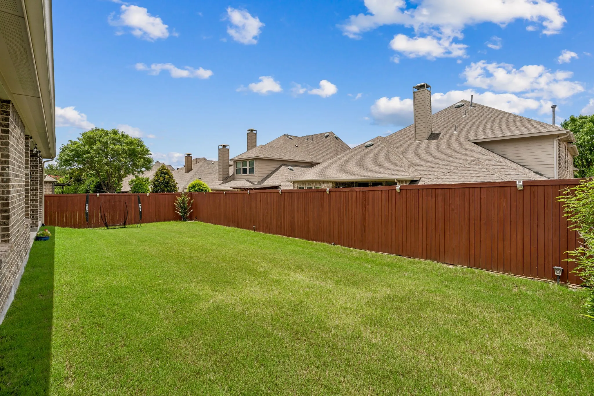 Expansive green lawn with a newly stained wood privacy fence