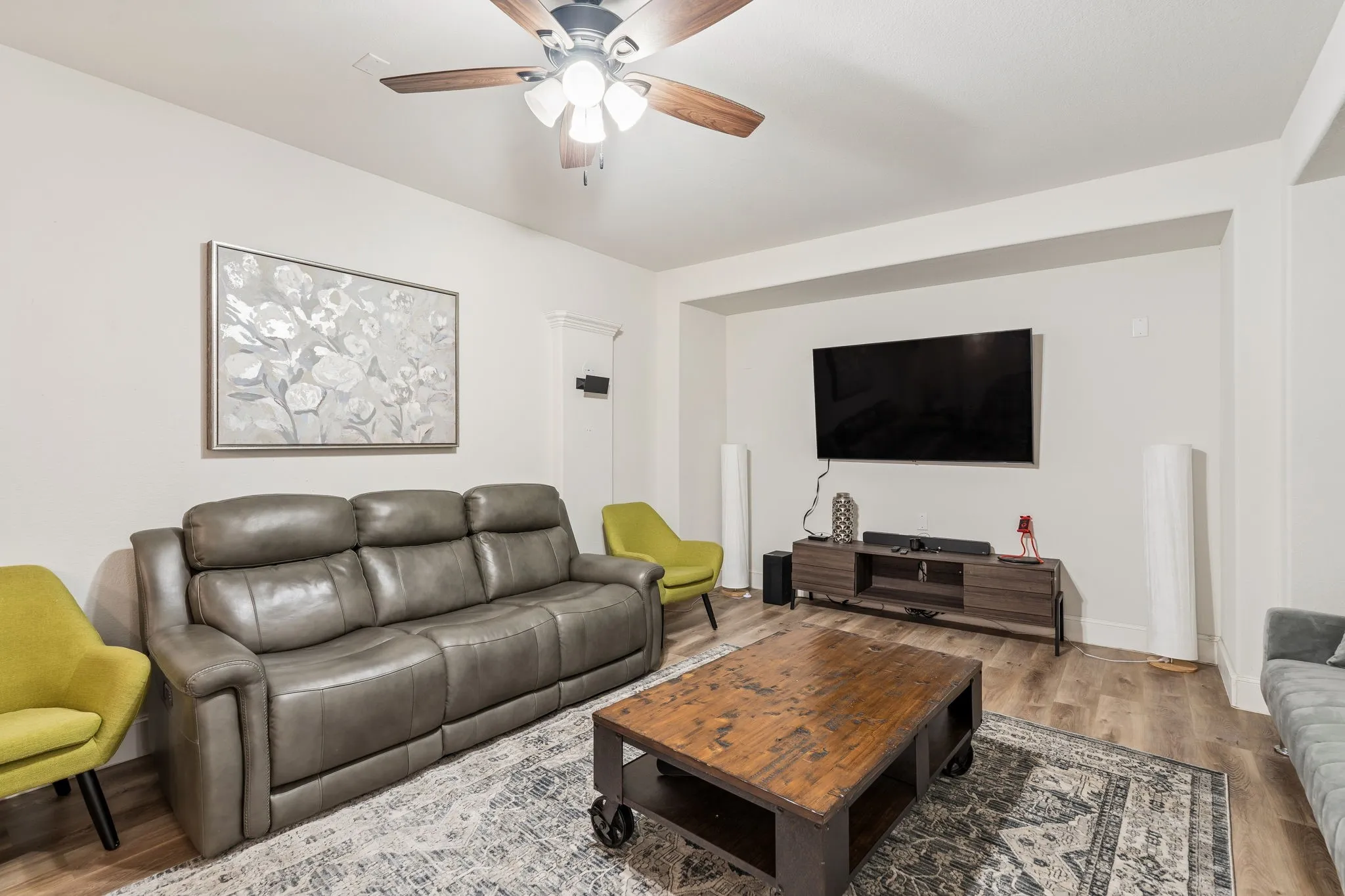 Living area featuring wood-finish flooring, recessed wall niche, and a ceiling fan with integrated lighting