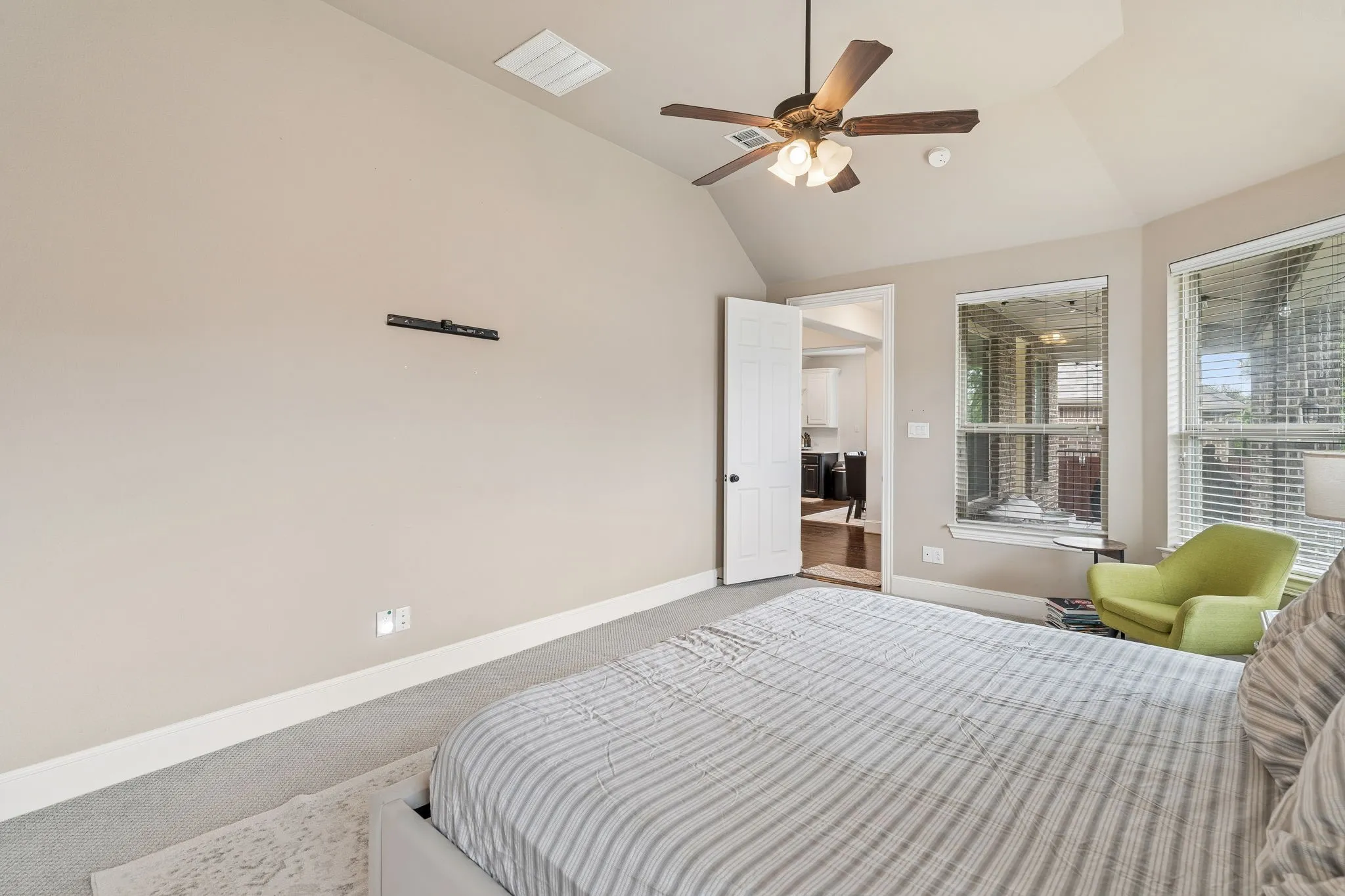 Carpeted room featuring a vaulted ceiling with a ceiling fan, two windows with blinds, and white trim