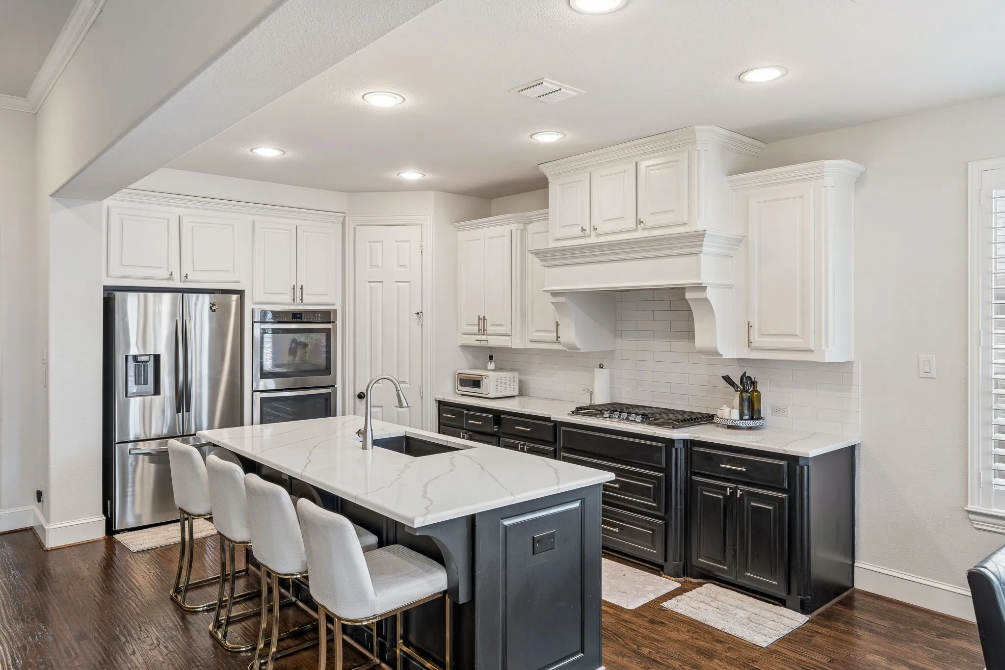 Kitchen featuring dark wood-finish flooring, a two-tone cabinetry design, stainless steel appliances, a built-in double oven, and recessed lighting