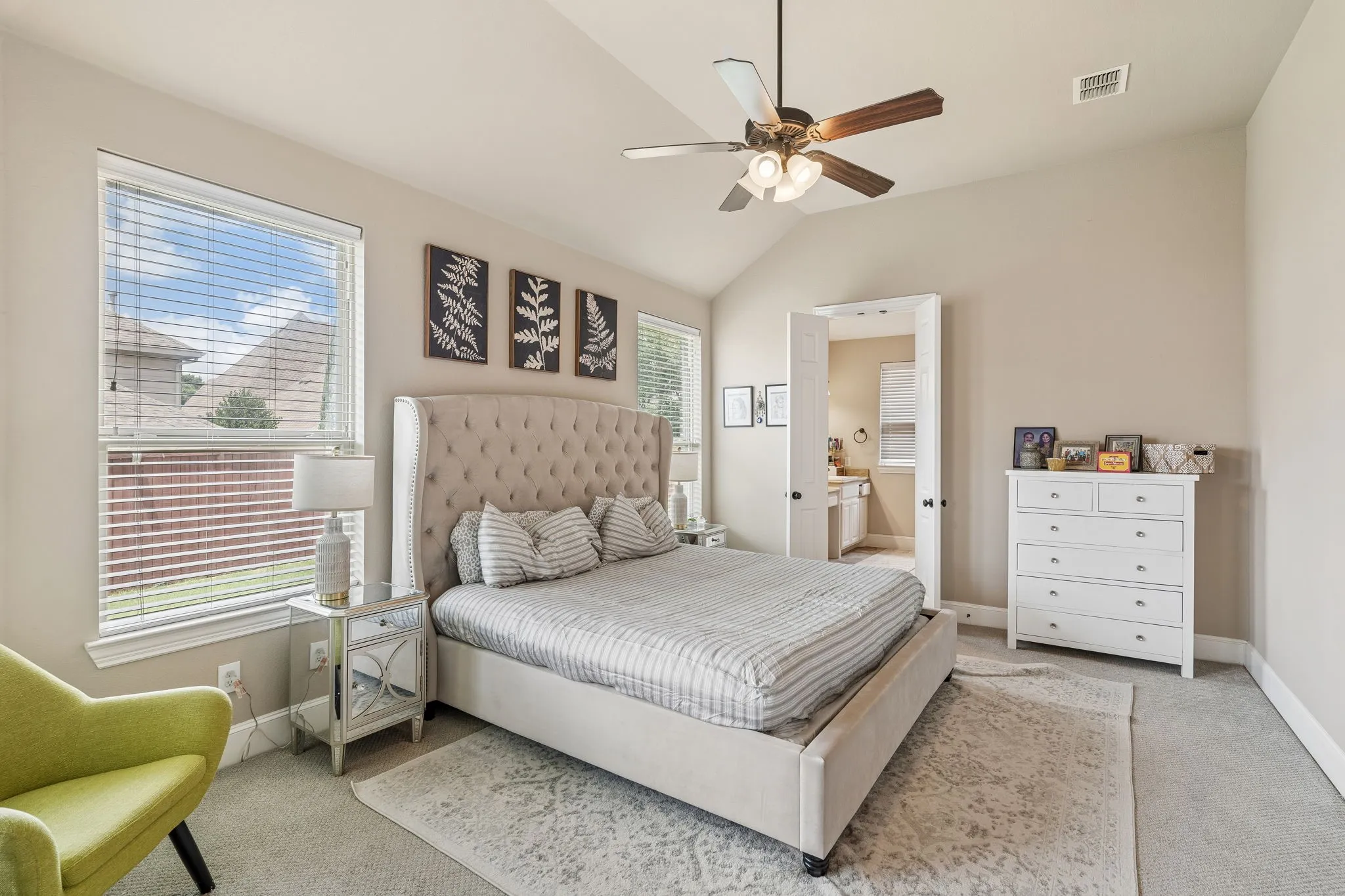 Vaulted ceiling bedroom featuring a ceiling fan with integrated lighting, two windows with blinds, and carpet flooring