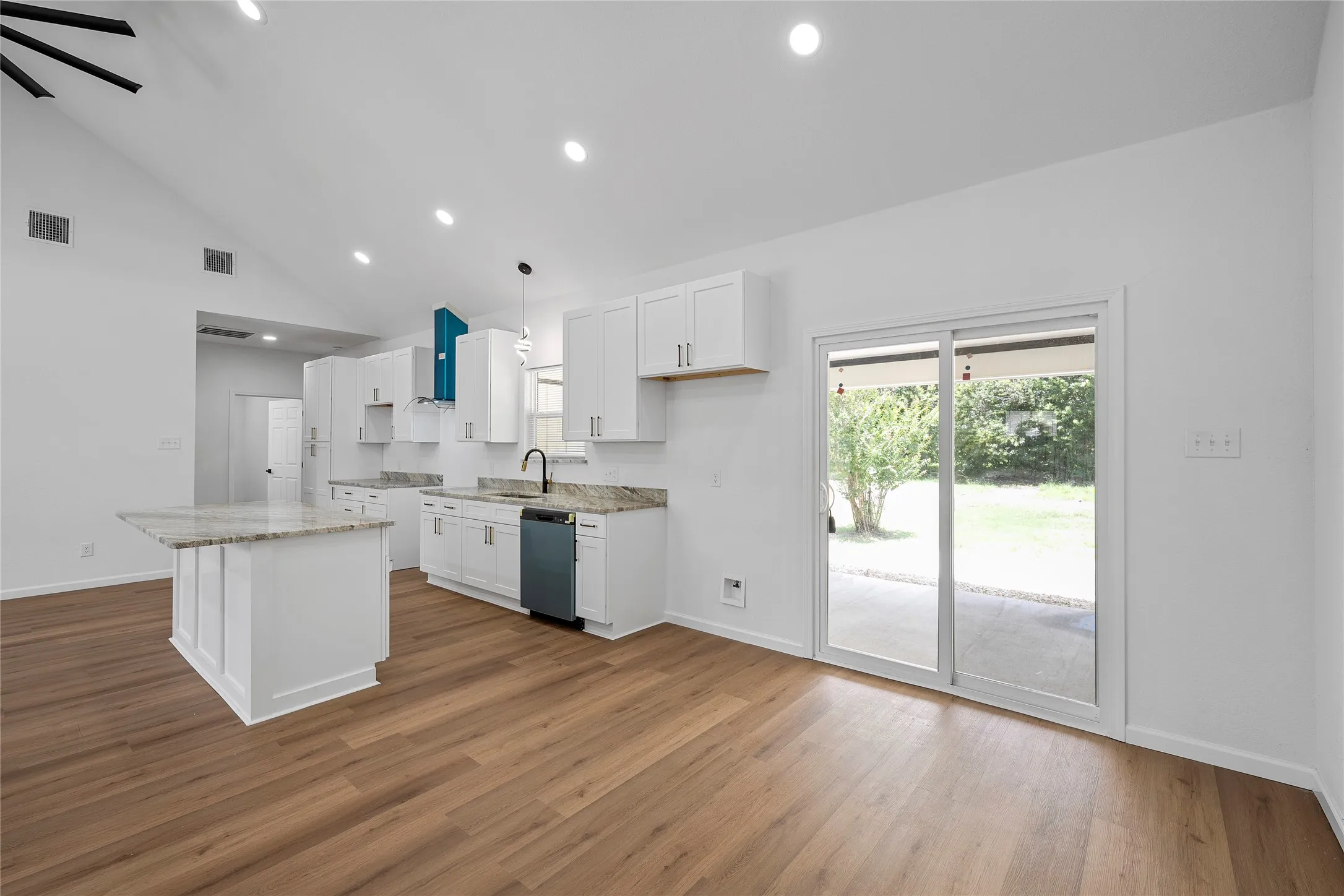 Open-concept living space featuring a vaulted ceiling, wood-finish flooring, and recessed lighting
