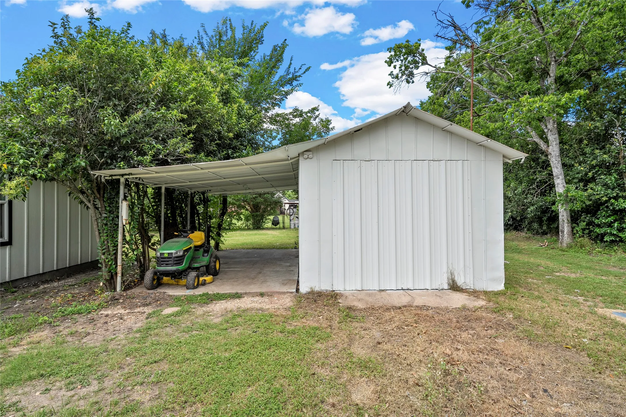 Detached storage building with white corrugated metal siding and a pitched roof