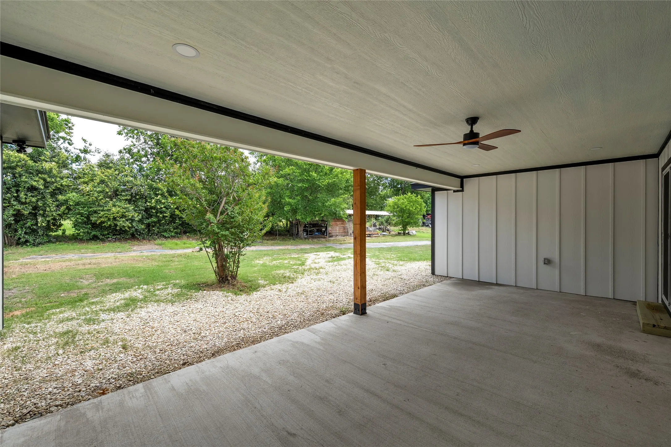Covered concrete patio with a wood-finish ceiling fan, recessed lighting, and a wood post