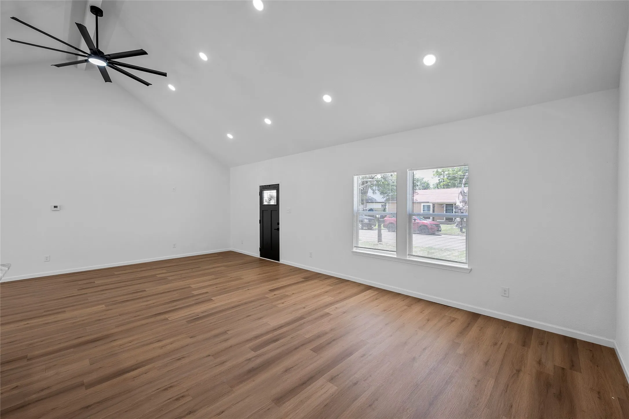 Expansive room featuring a vaulted ceiling and wood-finish flooring