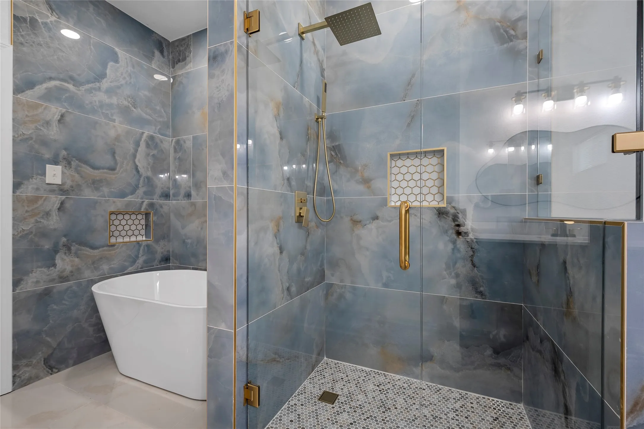 Spacious bathroom featuring a freestanding tub and a glass-enclosed shower with gold-tone fixtures
