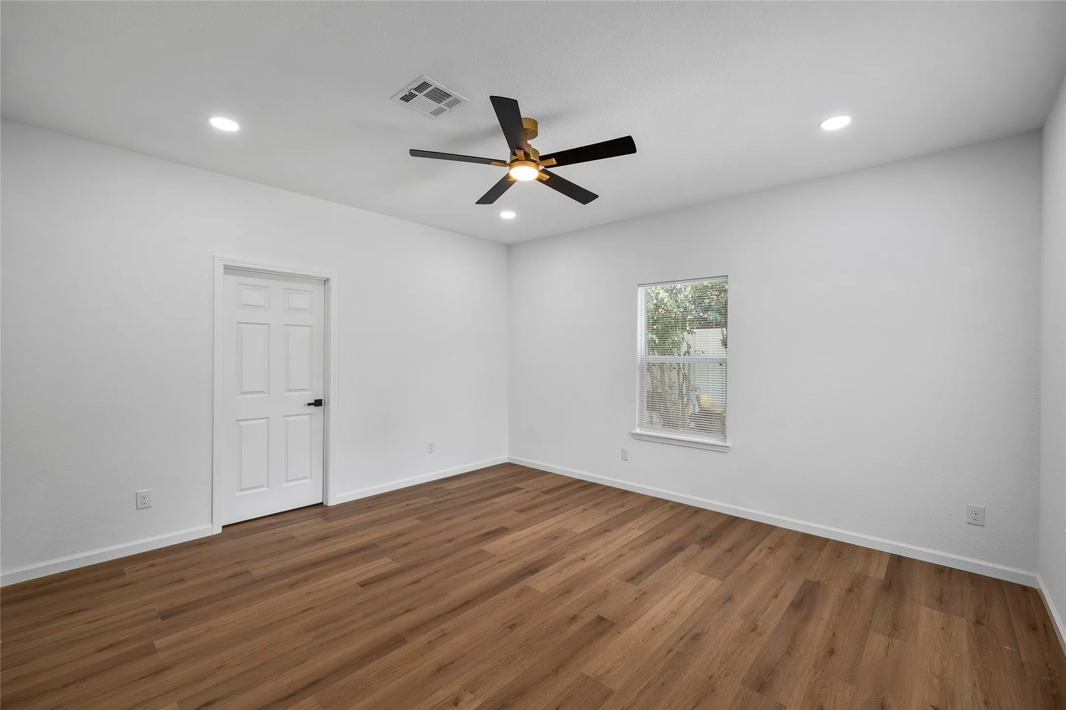 Spacious room featuring wood-finish flooring, recessed lighting, and a contemporary ceiling fan