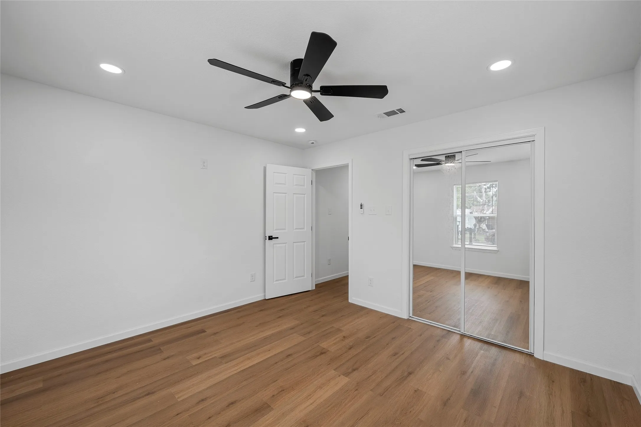 Bedroom featuring wood-finish flooring, white walls, recessed lighting, and a contemporary ceiling fan