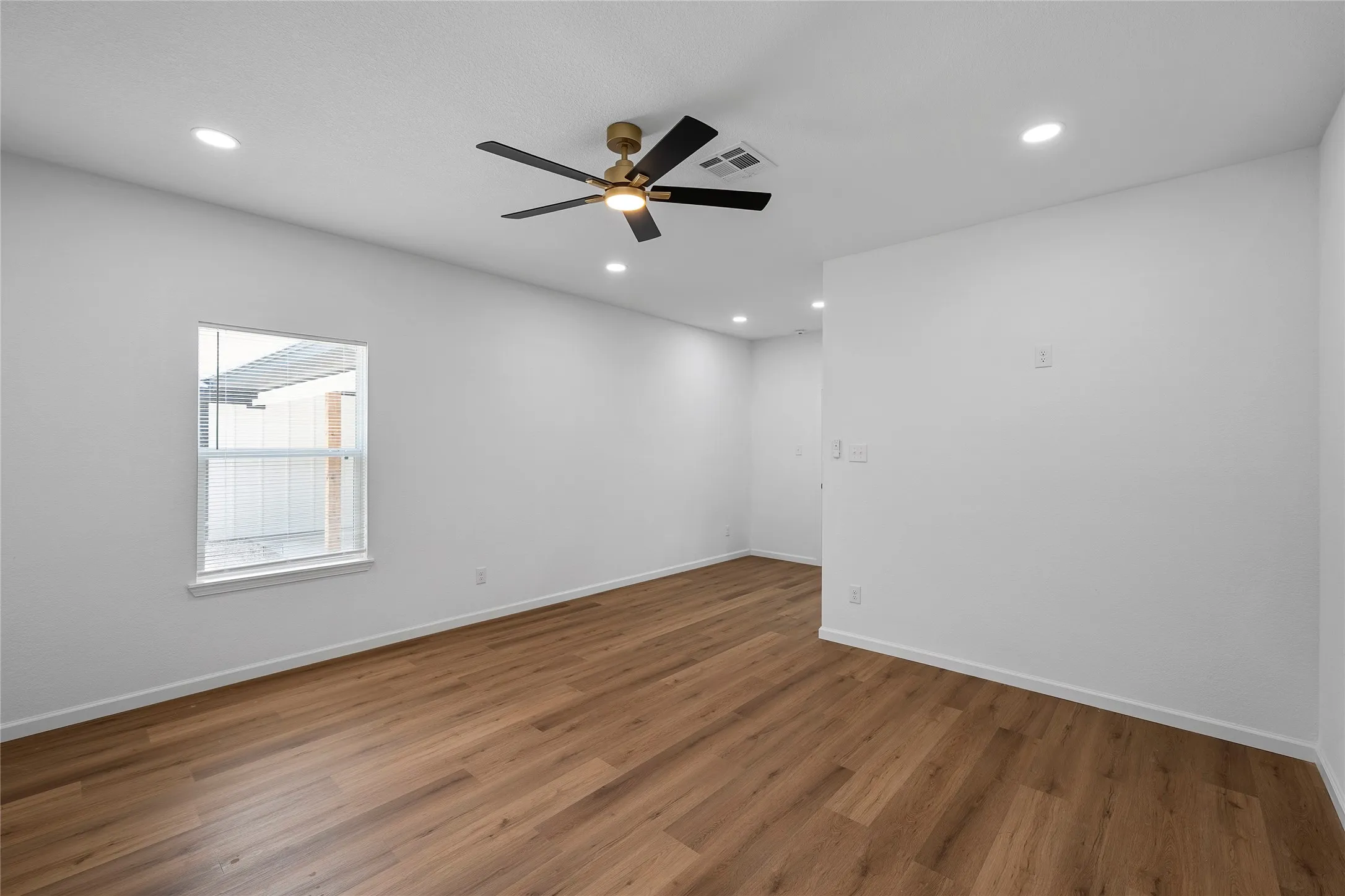 Open-concept room featuring wood-finish flooring, white walls, and a contemporary ceiling fan