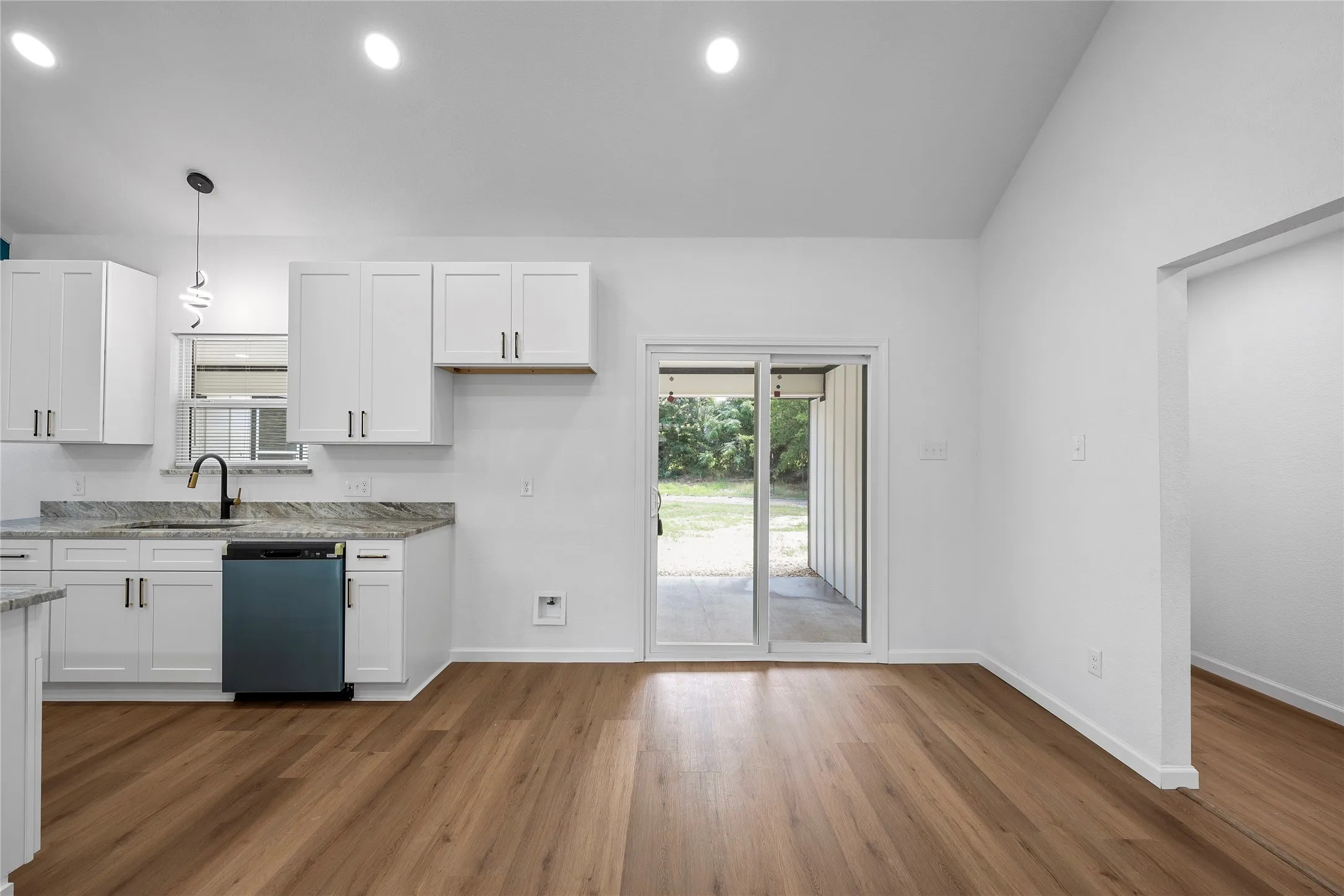 Kitchen featuring white cabinetry, stone countertops, a black appliance, wood-finish flooring, and sliding glass doors to the exterior