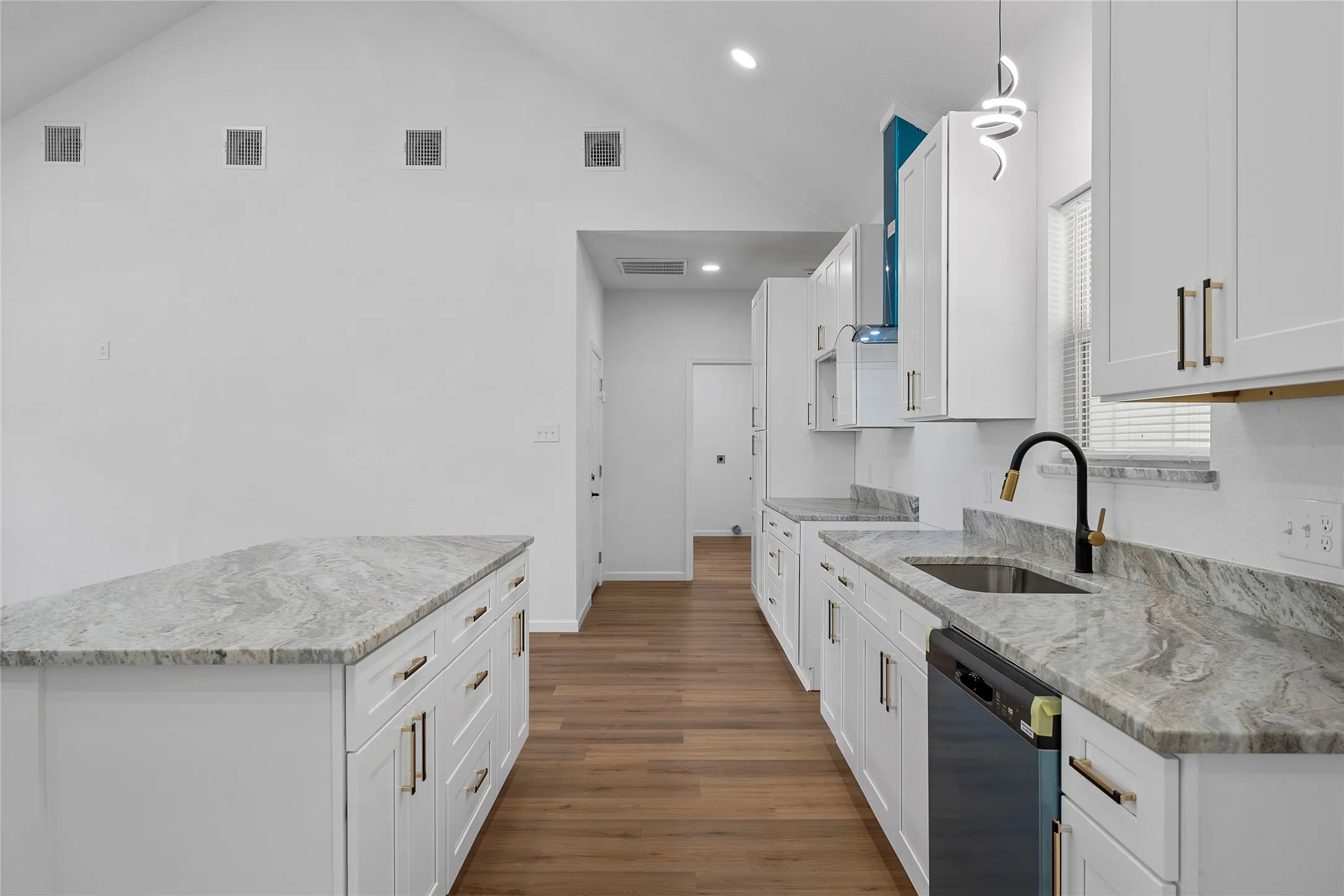 Kitchen featuring a vaulted ceiling and wood-finish flooring