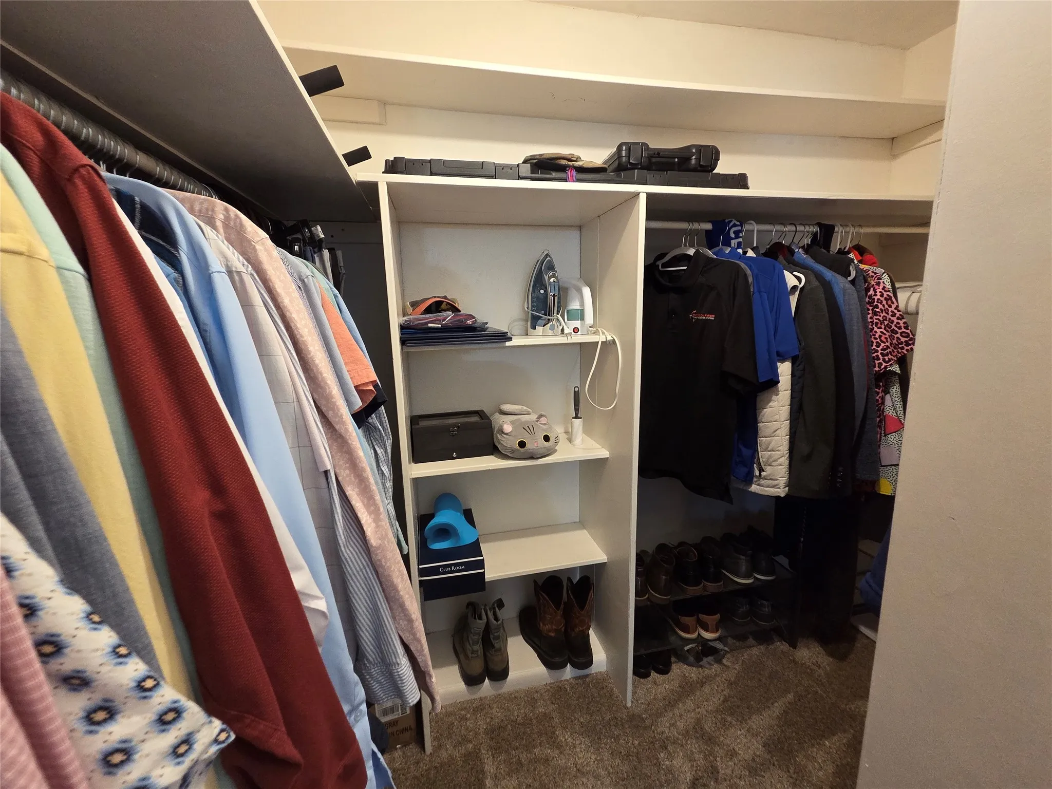 Built-in closet system featuring multiple hanging rods, adjustable shelving, and carpeted flooring