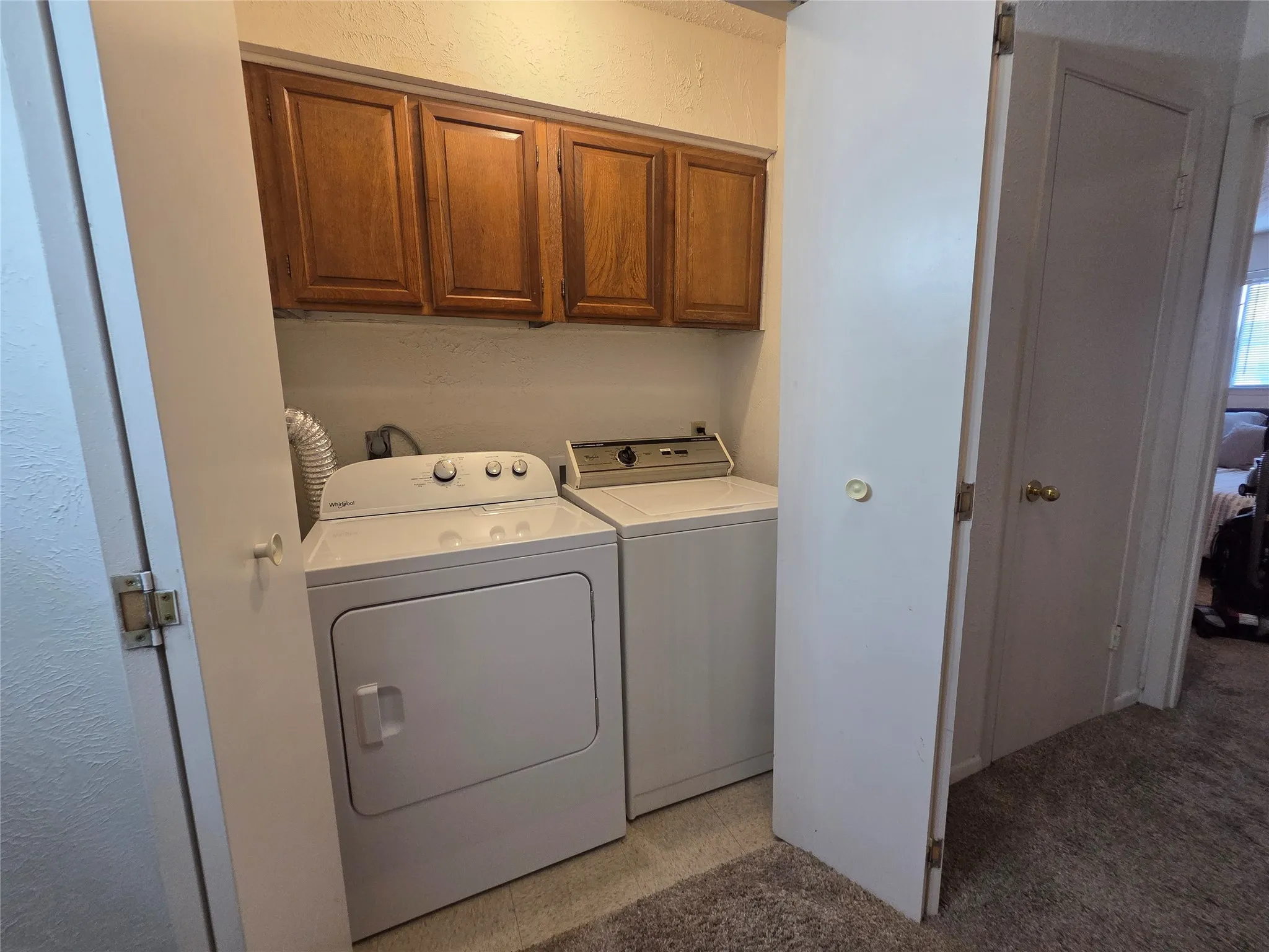 Dedicated laundry area featuring overhead wood-finish cabinetry