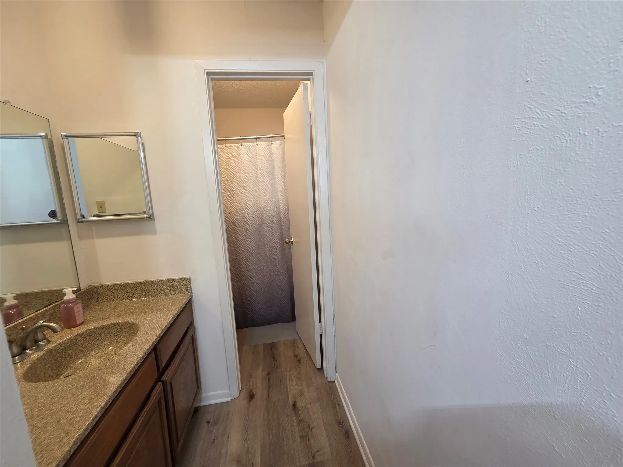 Bathroom vanity featuring a stone-finish countertop with an integrated sink and brushed nickel faucet
