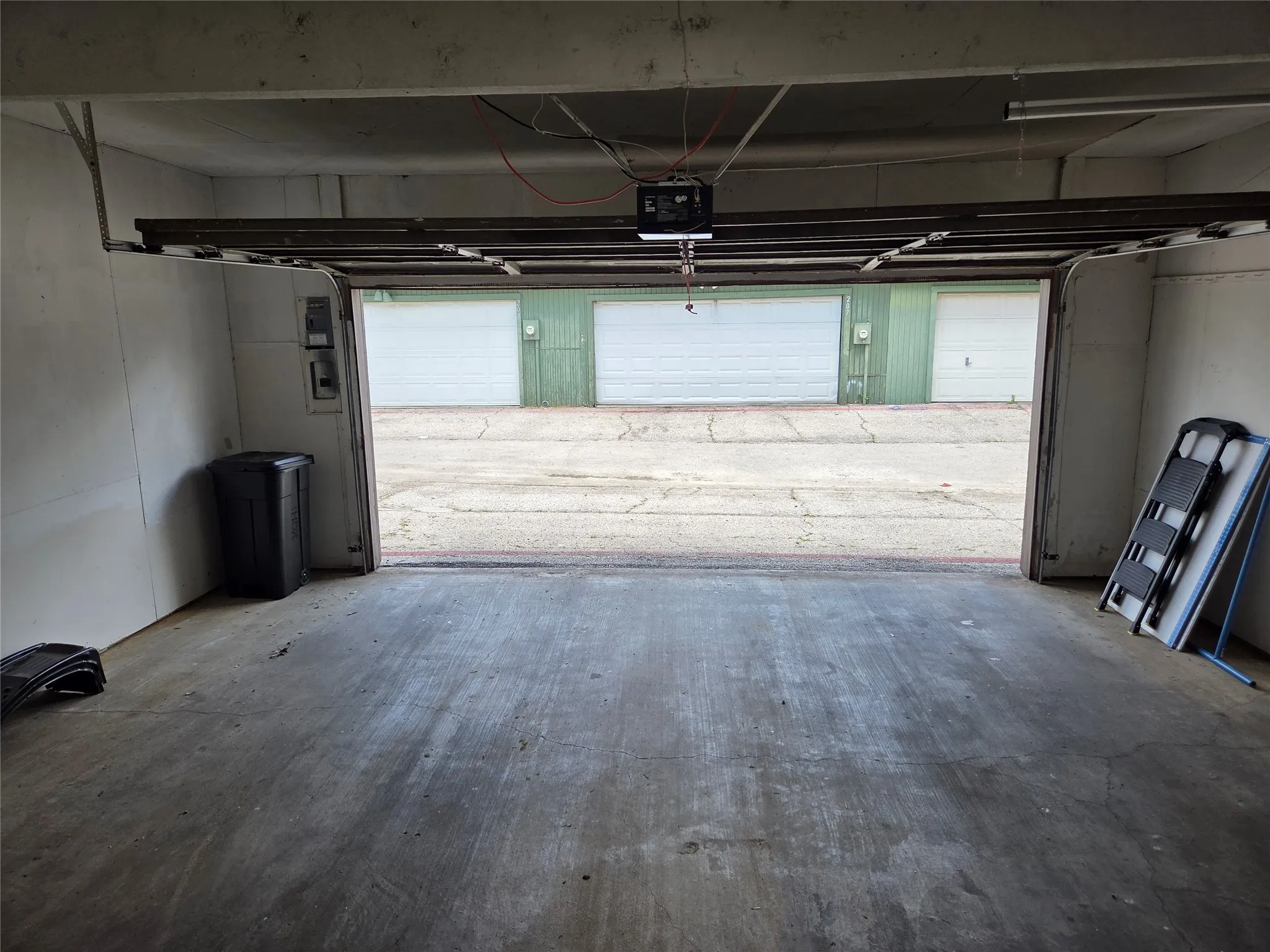 Spacious garage featuring a concrete floor, white walls, and an overhead garage door opener mechanism